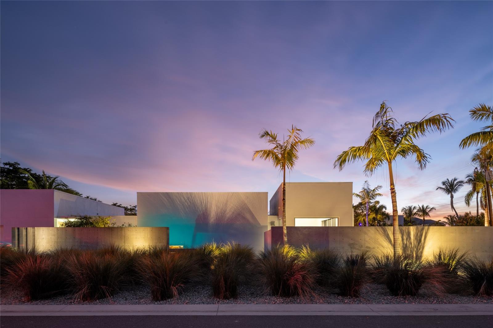 In the exclusive Lido Shores neighborhood, a community renowned for its architectural significance, this striking modern home stands as a testament to the visionary work of renowned architect Guy Peterson. Defined by clean lines, open spaces, and modern coastal tranquility, the residence embodies the essence of Sarasota’s contemporary aesthetic while offering an atmosphere of refined luxury. Floor-to-ceiling windows and doors create an airy, light-filled environment, blurring the lines between indoors and out. A thoughtful transformation in 2022 introduced a new dining area, a family room that doubles as a library, a dedicated laundry space and additional storage, all designed to enhance the home’s functionality without compromising its sleek, minimalist appeal. A newly enclosed garden and an updated pool area further elevate the outdoor experience, where lush landscaping and carefully curated spaces provide a sense of retreat. Beyond the walls, three distinct outdoor areas unfold, each offering its interpretation of serenity. A front courtyard, framed by a tranquil water feature and a Japanese-inspired garden, sets a meditative tone upon arrival. At the heart of the home, a lap pool and heated spa serve as the focal point of the central courtyard, where a Wolf outdoor grill and ample lounge space invite effortless entertaining. The third outdoor retreat, privately accessed from the primary suite, offers a secluded escape, reinforcing the home’s thoughtful approach to privacy and relaxation. The living spaces are defined by an understated elegance, where natural light and architectural precision take center stage. The open-concept design seamlessly integrates the main living area, dining space, and gourmet kitchen, which is appointed with top-tier Wolf and Sub-Zero appliances white quartz countertops and custom maple cabinetry. The primary suite, overlooking the inner courtyard, features a custom-designed closet system and private access to a serene outdoor seating area, creating a personal sanctuary within an exceptional home. Set within a community that grants its residents exclusive access to a private stretch of gulf-front beach, this residence is more than a home, it is an architectural statement, a retreat of contemporary sophistication and a rare opportunity to own a piece of Sarasota’s architectural legacy.