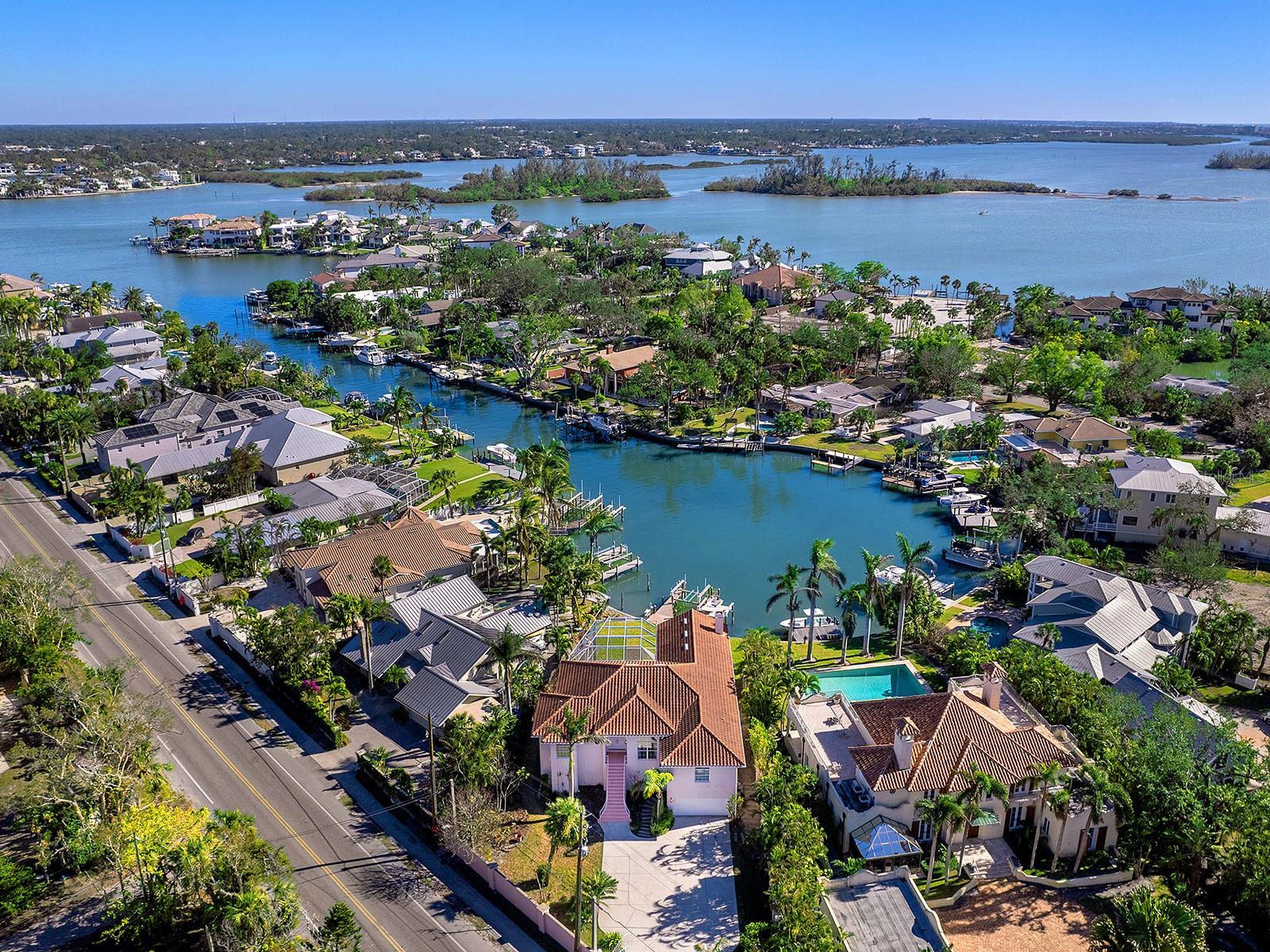 One or more photo(s) has been virtually staged. Experience the ultimate in coastal living with this two-story residence in the highly desirable Bay Island Shores on the world-renowned Siesta Key. Located in a prime waterfront setting, this all-concrete block home boasts a new tile roof in 2016 and offers unparalleled access to deep water and sailboat-friendly waters, making it the perfect haven for boating enthusiasts. The property, set on over a .35-acre lot, is nestled in a protected basin and features a newer dock with composite decking, complete with two boat lifts (12,000 and 4,500 pounds), installed in 2018—truly a boater’s paradise.The home’s elevated design places all living spaces on the second floor, ensuring captivating water views and privacy. A secure, walled gated entrance leads to a spacious garage area of nearly 3,000 square feet, offering abundant storage for vehicles, watercraft, outdoor equipment, just off the pool and spa. With room for multiple cars, golf carts, motorcycles, and kayaks, this area can also be transformed into a game room, home theater, fitness space, or sauna—catering to a variety of lifestyles and interests.Perfectly suited for both relaxation and entertaining, the home features high ceilings, crown molding, an elevator, and expansive living areas that flow effortlessly into the outdoors. A wraparound balcony, accessible from nearly every room, allows you to enjoy the island breeze and scenic surroundings, while multiple indoor and outdoor spaces provide plenty of room to host family and friends.Located on the desirable north end of Siesta Key, this property is just moments from the renowned Siesta Key Beach and the vibrant downtown Sarasota area. Additionally, being within the city of Sarasota, the property offers the flexibility of weekly rentals, making it an excellent investment opportunity. This exceptional home combines the best of island living with modern amenities—your coastal dream awaits.