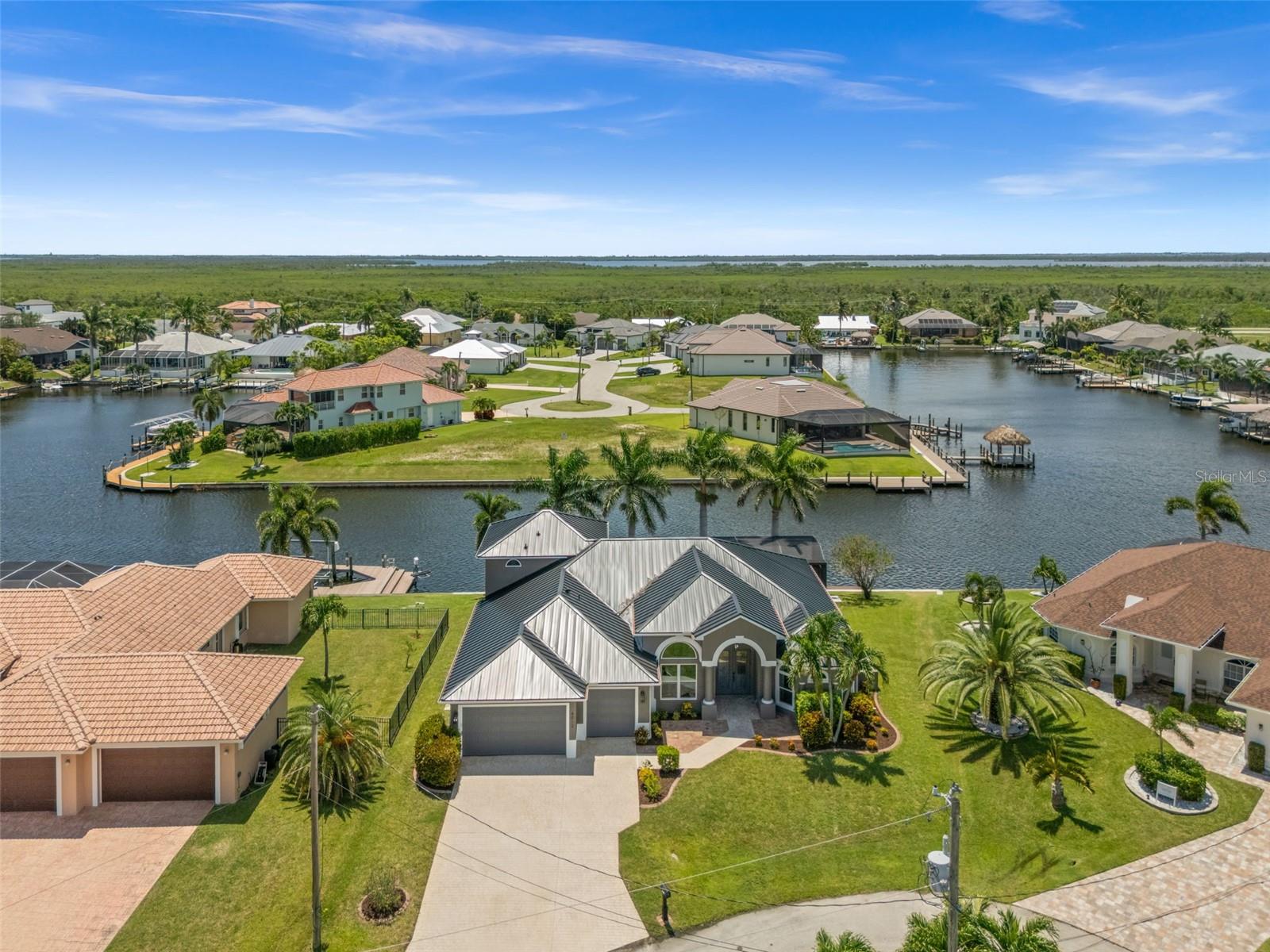 Welcome to 4012 SW 29th Ave, a beautifully updated Gulf Access pool home tucked away on a quiet cul-de-sac in Cape Coral’s highly sought-after Surfside neighborhood. Positioned on an oversized lot with 112 feet of waterfront, this home offers spectacular intersecting canal views and western exposure for picture-perfect sunsets. This home has been extensively remodeled and updated inside and out, starting with a new standing seam metal roof, new picture window pool cage, and updated paver pool deck. Inside, you’ll find new flooring throughout, a stunning new kitchen with quartz waterfall countertops, high-end Café appliances, a wine fridge, and a spacious walk-in butler’s pantry. The open-concept great room is filled with natural light and flows seamlessly to the large covered lanai through glass French doors. Outdoors, enjoy the heated 38' lap-style pool and built-in spa, paver tile pool deck, outdoor shower, and amazing water views. The primary suite offers high tray ceilings, French doors to the lanai, a walk-in closet plus a second closet, and a fully remodeled bath featuring dual sinks, a freestanding tub, and a luxurious glass-walled spa shower. Bedroom 2 has direct access to the guest bath and French doors leading outside, while Bedroom 3 features its own private bath and walk-in closet. Bedroom 4, currently used as an office, is filled with light from arched windows. Upstairs, a spacious loft with a full bath, walk-in closet, and French doors to the balcony with commanding water views serves as a flexible living area, perfect for a media room or office, or it could be converted to a fifth bedroom or in-law suite. There’s also a dedicated pool bath, and a laundry room with a washer and dryer that match the other appliances. With tall volume ceilings throughout, impact-resistant windows and doors, and elegant finishes at every turn, this home lives like new. Situated minutes from everything Cape Coral has to offer and just one bridge and no lock to open water, this is the ideal waterfront retreat for year-round or seasonal living.