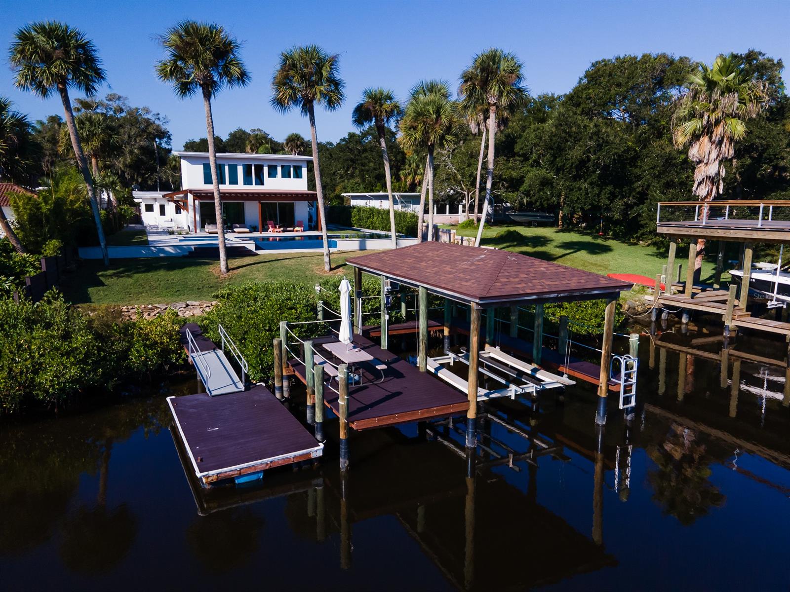 For the Buyer that seeks minimalism and high style (Palm Springs meets Miami) combined with direct waterfront living that is close to everything NSB, this totally renovated 1951 Mid Century Modern pool home will check all the boxes with no expenses spared. Enjoy an estate-sized lot with 84' of DIRECT RIVER FRONTAGE & boat house w/ 10K lift and floating dock. Enter this home through the custom Eurowall swivel front door and look out the massive Eurowall custom-made sliding glass doors. You'll think you've stepped into a gallery of awe-inspired views and finishes. The old Florida Hickory tree that was taken down on the property was milled for the hallway wall and stair risers, adding history. The living room, hallway and kitchen look out onto a courtyard patio that features a waterfall that spills into a long water feature around the side of the home and connects to the pool in the rear of property. The kitchen is adorned with custom cabinets, quartz counters, BLUM stainless steel hardware and drawers (same as used on yachts), custom tile backsplash and high-end appliances (Gaggenau, Miele, True, Subzero) including an ice machine and built-in coffee/espresso machine. All bedrooms are complete with built-ins and have en suite baths that will elevate the senses. There’s an office with built-ins as well. All interior doors are custom Emtek solid oak with Soss hidden yacht hinges. The Owner’s suite captures one of the best views in all of NSB. The master bath is also sure to wow, as will the custom walk-in closet. The outdoor space has Italian porcelain pavers & coping, fully automated pool w/ infinity edge, waterfall, spa & lighted bubblers. This historic River Arts district home is walkable to Canal St for dining, shopping and entertainment, 5 minutes to the beach! WATCH THE VIRTUAL TOUR OF THIS WORK OF ART. HOME FEATURES LIST ATTACHED. ALL INFORMATION ASSUMED ACCURATE BUT NOT GUARANTEED. MEASUREMENTS ARE APPROXIMATE. BUYERS & THEIR AGENTS TO VERIFY ALL INFORMATION. ;Water: City