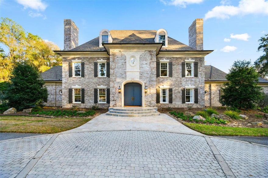 Set on 6.81 secluded acres in the exclusive Tomoka Hills enclave, this extraordinary French Provincial estate offers a rare blend of privacy, elegance, and resort-style living. Exceptionally designed and spanning nearly 6,000 square feet in the main home and over 2000sf in the new guest house, the residence showcases a thoughtfully designed floor plan that flows effortlessly for both comfortable daily living and sophisticated entertaining.

Remodeled by local custom builders, the home features impeccable craftsmanship and high-end custom details throughout, reflecting remarkable attention to fit and finish. The main residence includes four spacious bedroom suites, all en suite, along with 5.5 bathrooms.

Inside, gorgeous hardwood floors unify the entire home while a dramatic two-story foyer with intricate woodwork welcomes guests and frames immediate views through French doors to the pool and completely private backyard. The first floor offers multiple gathering spaces, including a sitting room with fireplace, formal dining room that flows through a Butler's Pantry to the kitchen and a spacious family room with a nearby half bath and wine bar—ideal for entertaining.

The luxurious primary wing serves as a private retreat, featuring a sitting room (or office), a spa-inspired bath with a free standing tub, separate marble vanities, and a large walk-in shower finished in Calacatta marble with rain shower head and multiple shower heads. A large dressing room with an extensive organizational closet system completes the suite.

Designed with entertaining in mind, the formal dining room connects to the stunning chef’s kitchen through a separate butler’s pantry, providing the perfect space for catering prep and seamless hosting. Upstairs, a gracious landing with open-air balcony access leads to three additional private suites, plus a flexible bonus room with built ins.

Adding tremendous value and versatility to the property is a newly constructed 2,100-square-foot detached guest house. This luxurious residence offers two bedrooms (one BR is currently used as a GYM with rubber mat flooring), one bathroom, a spacious living room, and a full high-end designer kitchen with premium finishes. Perfect for guests or extended stays, the guest house also features a large summer kitchen with motorized screens, creating a seamless indoor-outdoor living experience that flows beautifully to the resort-style pool area. With its designer finishes, spacious layout, and luxurious feel, this guest residence functions as a private retreat within the estate.

This remarkable property combines refined European-inspired architecture, modern luxury updates, and expansive grounds, creating a truly exceptional estate setting located in a prime location in SW Gainesville.