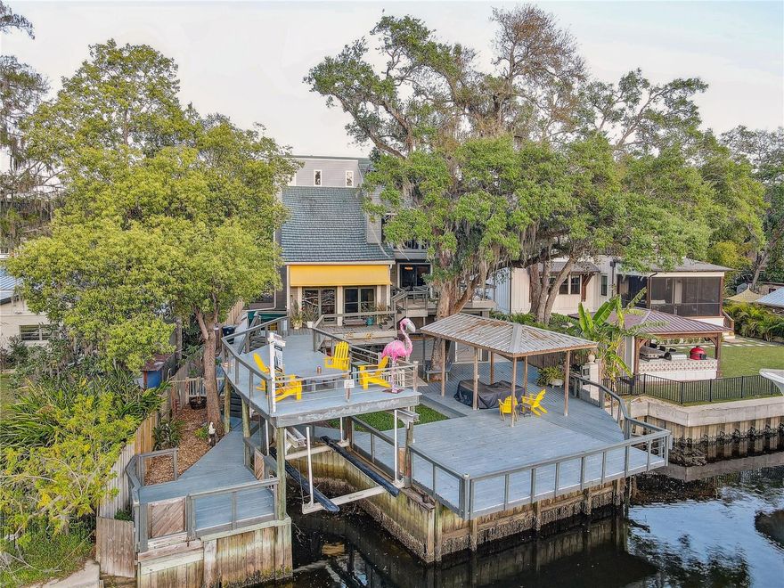 Check out this Rare opportunity to live WATERFRONT and step into a world of nostalgia and charm with this cozy vintage home that features 3 Bedrooms, 3 bathrooms and a 4 CAR CARPORT for ample parking in the Booming Seminole Heights neighborhood. Sitting on over 1/3 of an acre this unique tri-level retreat rests gracefully on STILTS with a BOAT GARAGE offering stunning waterfront views and ACCESS TO THE OPEN BAY ideal for a lifestyle of comfort and relaxation. As you arrive, a PRIVATE ELECTRIC GATE welcomes you to a beautifully landscaped property featuring a METAL ROOF (with a 40 year warranty), a LONG ROUNDABOUT driveway, and a 10x20 storage shed equipped with electricity and AC. The front yard is adorned with three raised garden beds, a bowling ball garden, birdhouses, and an OUTDOOR GYM area under the home while a dry bar and butcher block counters add to the home's rustic charm. With transferable LOW FLOOD INSURANCE ($810/year) this home is designed for peace of mind. Out back, MULTI-LEVEL hardwood PARTY DECKS overlook the HILLSBOROUGH RIVER, while a boat garage/dock and a metal roof pergola deck offer the perfect setting for entertaining. Situated across from Lowry Park, with no neighbors directly across the river, this home delivers an unbeatable combination of privacy and breathtaking scenery. A canvas awning elegantly covers the front stairs, adding to the home's welcoming appeal. Inside, walking into the arched yellow double doors that lead to a grand entry with SOARING 22 FT ceilings. Step down into the cozy living room, where wood-beam textured ceilings and a wood-burning fireplace create a warm and inviting ambiance. Sliding doors open to the deck, blending indoor and outdoor living. A wrought iron staircase leads to the upper floors, adding to the home's vintage charm. The master bedroom is a true retreat, featuring a spiral staircase to an ADDITIONAL LOFT 17.5-ft ceilings, two walk-in closets, moonlights, plantation shutters, and a spa-like en-suite. The master bath boasts a frameless hanging wall-mount double sink vanity, a garden tub, and a stand-up shower. The kitchen is a chef's delight with stainless steel appliances, a cooking island, a metal farm sink, granite countertops, two pantries, and ample storage. A farmhouse-style rectangular chandelier adds elegance. The dining room features built-in cabinets, sliders to the outside, and a charming arched "hobbit door" leading to the outdoor deck. Bedroom 2 is a private oasis with an en-suite bathroom, two closets, and picturesque bay windows. The bathroom showcases a vintage clawfoot tub, tile flooring, and classic wainscoting walls. Bedroom 3 offers another cozy LOFT with a ladder and also sliding doors leading to the deck. The home features three sliders on the second floor, two on the third floor, and French doors opening to a PRIVATE BALCONY off the kitchen—creating a seamless indoor-outdoor flow. With its unique character and unbeatable waterfront location, this home is a rare gem that blends vintage charm with modern comforts For history lovers, the remains of the Confederate blockade runner, the sloop Kate Dale, which was sunk during the 1863 Naval raid on Ballast Point, are visible directly off the south end of the seal wall during low tides. Conveniently located in Seminole Heights with easy access to an abundance of restaurants, parks, access to I275, downtown, the airport and beaches. You don't want to miss your chance to own this rare riverfront sanctuary.