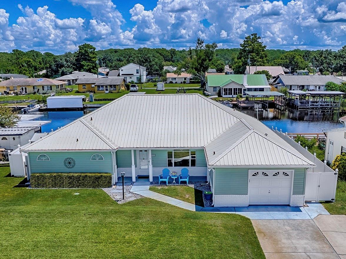 One or more photo(s) has been virtually staged. Pristine Waterfront home in Lake Harris Shores, Tavares, America's Seaplane City! Discover the charm of this premier waterfront community nestled along the 76,000-acre Harris Chain of Lakes, perfect for world-class fishing, boating, water-sports, and recreation. This stunning waterfront home offers direct access to the water with a newly updated, covered electric boat lift and an expansive covered deck just steps from your door—ideal for entertaining, fishing or soaking in serene canal views teeming with wildlife, birds, and all kinds of watercraft, just moments from Lake Harris.
Step inside to a bright, open-concept layout with a split floor plan, freshly painted inside and out, featuring engineered hardwood floors, stainless steel appliances, real wood cabinetry, and elegantly updated primary and guest bathrooms. The spacious primary suite includes a large walk-in closet and an adjacent bonus room with breathtaking water views, perfect for a private retreat, home office, or creative space. Water views extend throughout the home, captivating you from the living area, Florida room, kitchen island/breakfast nook, and dining space.
Built for lasting comfort, this move-in-ready home boasts a durable metal roof, a modern septic system, and numerous upgrades. Enjoy the island-like ambiance from your front porch as well, with pleasant water views. Additional features include a metal seawall, white vinyl privacy fence, canal irrigation, electrical outlets with a spa/hot tub hookup on the deck, and a transferable home warranty.
Lake Harris Shores offers a welcoming clubhouse, private community boat launch, and beach on Lake Harris. Don’t miss your chance to experience this waterfront gem—schedule a showing today!