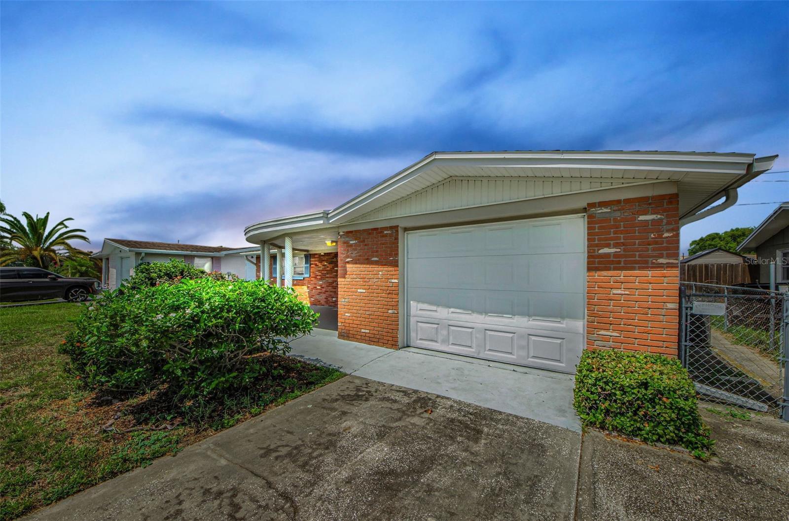 Welcome to this charming two-bedroom Old-Florida gem where comfort meets function. Brimming with natural light, this thoughtfully designed home features a desirable split floor plan and an open-concept layout, complemented by a mix of easy-care tile and plush carpeting throughout. The kitchen overlooks the dining and living areas and includes a long breakfast bar ideal for casual meals or keeping the chef company. Generous ceiling-to-floor pantry cabinetry ensures you’ll have plenty of storage space. Just off the kitchen, walk through the door leading to the extra-wide one-car garage with a washer and dryer tucked out of the way. To the right is a convenient air-conditioned second bathroom, complete with a tiled walk-in shower and a toilet. A versatile bonus room off the main living area provides endless possibilities, think home office, playroom, creative space, or reading retreat. Step outside the back door into the fenced backyard with ample space for entertaining, gardening, or giving your pets room to roam. Lovingly maintained and move-in ready, this delightful home is waiting to welcome its next chapter. Also worth mentioning is that this home has weathered many Florida storms since 1969 without a flood! Roof 2015, AC 2012