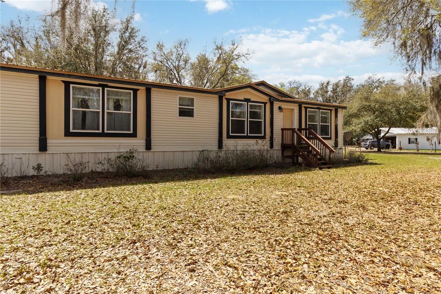 First Time Ever on the Market Peaceful Country Living. Welcome to this charming 3-bedroom, 2-bathroom manufactured home sitting on 1.12 acres, tucked away in a quiet neighborhood where you can truly enjoy the beauty of Florida living. Surrounded by open space and mature trees, the property feels lively, private, and breathable perfect for those seeking tranquility with room to grow.  Inside, the home features a bright open floor plan enhanced by brand-new vinyl wood flooring and elegant crown moldings, creating a warm and inviting atmosphere. Large windows allow natural light to fill the home, while ceiling fans in every bedroom help keep the home comfortable year-round. The living room offers a cozy focal point with an electric fireplace that can easily be converted to wood-burning, adding charm and warmth to the space.  The kitchen is equipped with new appliances and beautiful wooden cabinets. The primary suite provides a relaxing retreat with a double-sink vanity, standing shower, and soaking tub. A convenient indoor laundry area adds everyday practicality.  Step outside and enjoy the sounds of rain dancing on the recently redone metal roof, or relax on the wooden deck in the back, perfect for gatherings or peaceful evenings outdoors. The property also includes an accessible ramp, detached carport, shed for additional storage, and a detached garage. With over an acre of land, there is plenty of space for your toys, animals, or simply enjoying the open Florida countryside. This special property offers the perfect blend of comfort, space, and peaceful surroundings a rare opportunity and the first time it has ever been offered for sale. This property qualifies for a USDA loan, which means eligible buyers may purchase the home with no down payment. Excellent option for first-time homebuyers or anyone looking to purchase a home with little upfront cost while still enjoying the benefits of homeownership.