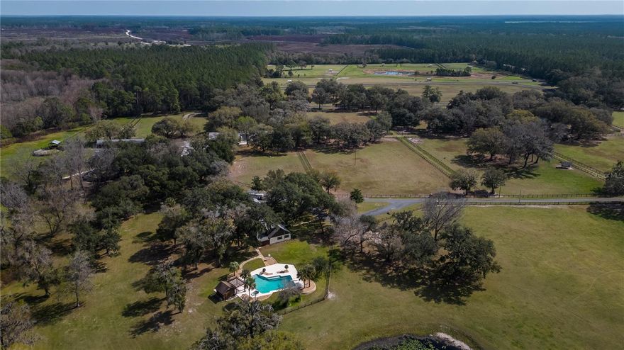 Experience the legacy of renowned horseman Clyde D. Rice and his wife Jean Rice with this storied farm now offered for sale! Nestled on 185+/- acres of picturesque Central Florida countryside, this comprehensive training facility is ideal for thoroughbred operations or conversion into a multi-disciplinary facility. Spread across 4 parcels, the property features 4 barns totaling 48 stalls, including a main training barn with fly spray systems, wash racks, tack and feed storage, equipment storage, barn office, and more. Numerous paddocks and pastures are scattered throughout the property, with additional room for expansion. Take advantage of the eurocizer and two round pens already established, and set up additional arenas and training areas as needed. The ½ mile irrigated dirt track, complete with starting gate and separate well, forms the centerpiece of the property.  The property boasts 4 residences, including a well-appointed 5-bedroom, 3.5-bath main home with over 5600 sq.ft. of space. Featuring tall, wood-beamed ceilings, skylights, and stunning views, the home includes a huge gas fireplace, wet-bar area with bar-style seating, exercise room with sauna, and a sparkling in-ground saltwater pool with gas heating and additional cabana with pergola. Updated with a new roof in 2012 and professionally replaced windows in 2018, the home is move-in ready.  Situated near Indian Lake State Forest and Indian Lake Prairie, the property provides ample opportunities for outdoor activities, including miles of riding and hiking trails. Enjoy the privacy and seclusion of country living while still remaining convenient to stores, restaurants, medical options, and equine service and retail providers throughout Ocala. Don't miss out on the chance to build your equestrian legacy on this amazing property with a rich history!