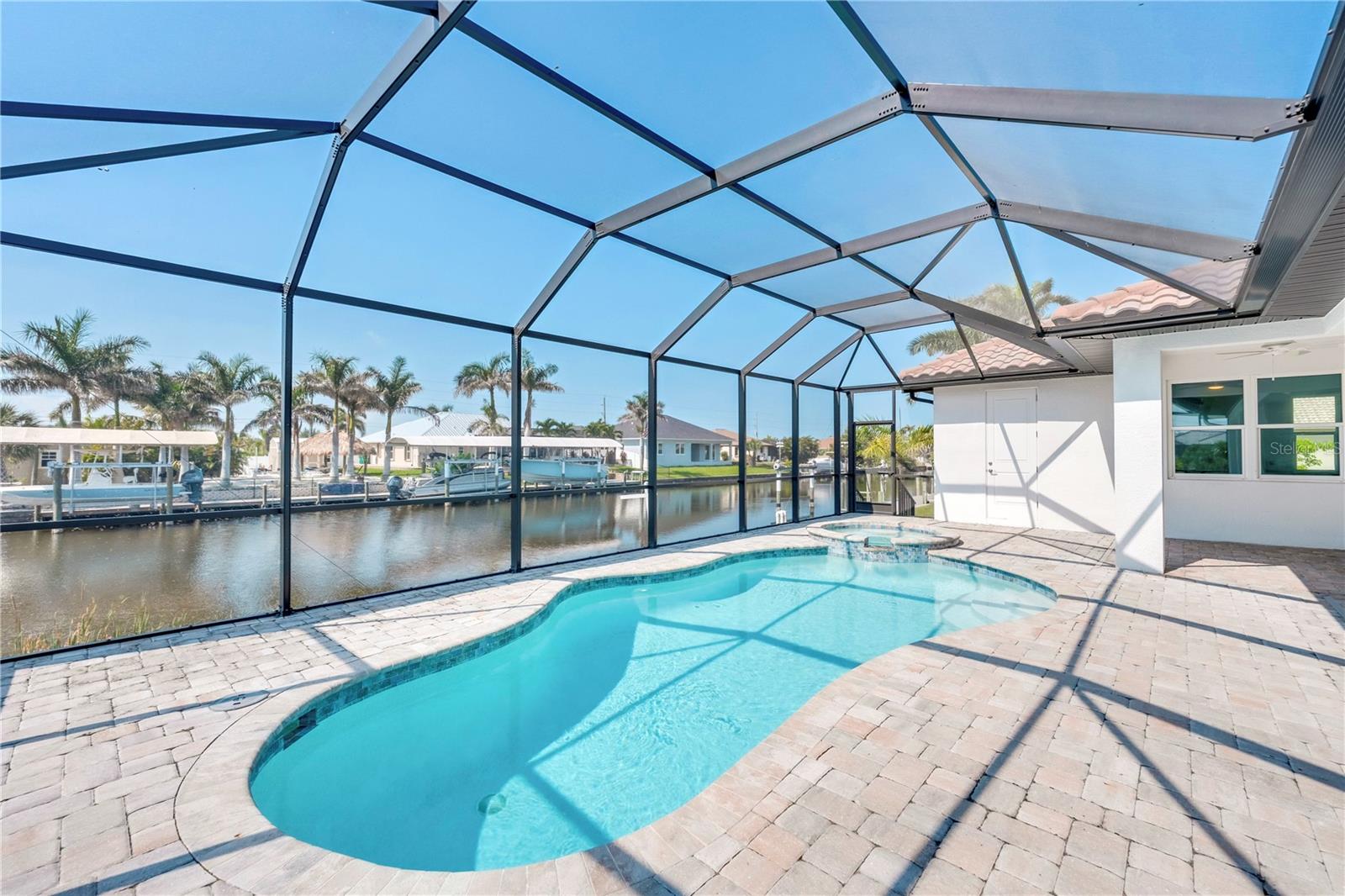 BRAND NEW, never lived in 3-bedroom, 3-bath, 3-car garage custom POOL home in SOUTH GULF COVE with DIRECT SAILBOAT ACCESS — no bridges, 7-minute boat ride to the lock and 15-minute boat ride to Charlotte Harbor! FROM YOUR COUCH TO THE HARBOR IN 15 MINUTES! BUILT IN 2022 and located on a prime canal-front lot with 80' of PRIVATE SEAWALL, this home offers luxury waterfront living at its finest. Hurricane ready with IMPACT WINDOWS and DOORS. The spacious SPLIT FLOOR plan features plank tile flooring throughout, soaring ceilings, and an open-concept design. The CHEF'S KITCHEN includes a gas burner cook top, pot filler, large island with built-in cabinetry, and high-end finishes. The OVERSIZED second and third bedrooms are ideal for guests, offering comfort and privacy. A pocket door separates these rooms from the main living area, creating a private guest wing. The third bedroom also features direct access to the pool bath, making it perfect for outdoor entertaining and extended stays.
The primary suite offers serene canal views, dual walk-in closets, a spa-style bath with soaking tub, and a large walk-in shower. Step outside to the expansive covered lanai — perfect for entertaining — featuring a HEATED SALTWATER pool with integrated SPA, outdoor kitchen, and southern exposure for all-day sun. The garage includes epoxy floors, and the home is nestled in a quiet neighborhood, ideal for relaxation and boating. This is a rare opportunity to own a move-in-ready waterfront home with Gulf access and luxury upgrades throughout. Call today to schedule your private showing. MOTIVATED SELLER!
