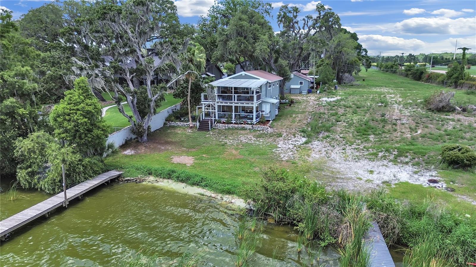 Welcome to this beautifully updated lakefront property on Lake Thonotosassa in Florida. The main home features two bedrooms and two bathrooms, with a spacious layout including cathedral ceilings, granite countertops, white shaker cabinetry, and luxury vinyl flooring. Enjoy lake views from the den and dining area, or relax on the upper balcony or the bottom porch. The main bedroom is on the first floor, including a walk-in closet and en suite bath. The home has newer appliances, a metal roof, and interior and exterior laundry hookups. In addition, the property includes an income-producing detached one-bedroom, one-bath accessory dwelling, a 25x40 RV carport, a 12x24 workshop with an attached open carport, and an exterior laundry room for tenants. A paved asphalt driveway leads from Knights Griffin Road to the rear of the property. A covered boat deck with pier completes this exceptional lakeside offering. You can fish, ski, and other water sports.