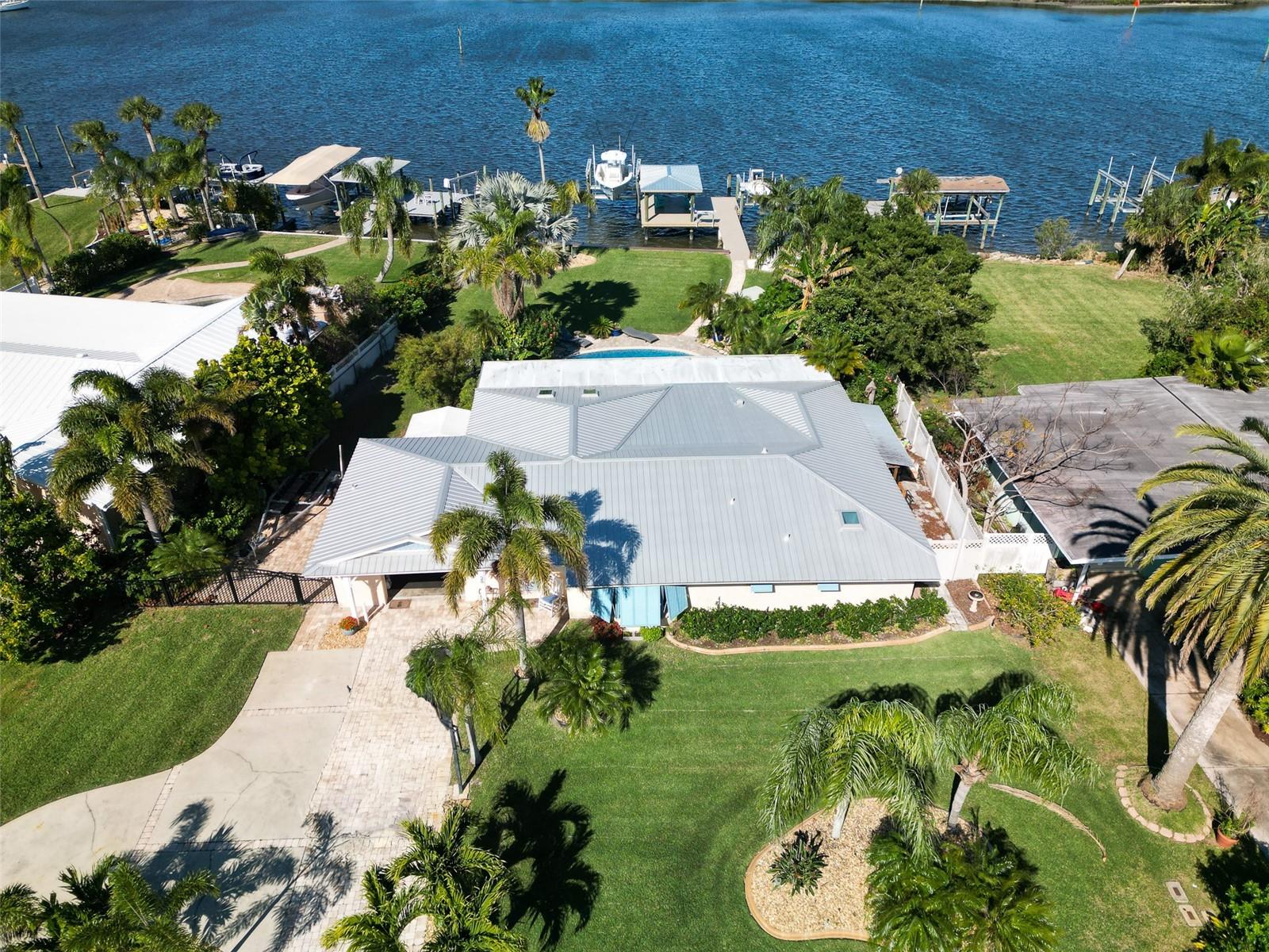Fantastic riverfront home with rare, deep water frontage and incredible views. Located on an exclusive stretch of Bouchelle Island, home to some of the most boater-friendly water in NSB, this awesome property boasts expansive, unobstructed views of the Intracoastal Waterway and offers direct & easy access to Ponce Inlet, the Disappearing Islands and the Atlantic Ocean. The oversized (84 x 179) lot features lush, tropical landscaping, boat/RV parking and a custom and newly resurfaced pool. Waterfront highlights include a brand new, covered dock with two lifts (18,000 libs & 10,0000 lbs) - both of which were installed in 2023, and a reinforced seawall and revetment. Inside the home you’ll find a fully renovated kitchen with all new appliances and high end granite countertops and a renovated guest bathroom. The outside of the home is a true oasis of entertaining, with built-in summer kitchen appliances, comfortable, covered dining and living areas, a gas fire pit and a zen Koi pond, full of fish and surrounded by fruit trees. Additional interior upgrades include new flooring, new electrical panels, a new fence and a new sprinkler system. Come live your best life on the best deep water in New Smyrna Beach.