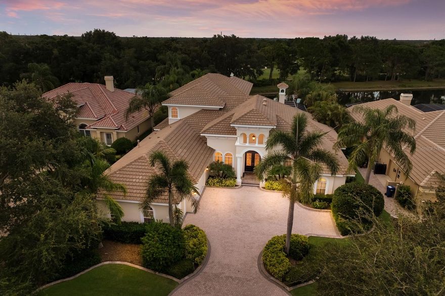 Positioned on serenely picturesque lake and golf course setting, this 5,474 square foot two-story estate in the exclusive and sought-after gated community of University Park Country Club is a custom built offering by Anchor Builders that showcases generously proportioned spaces, soaring ceilings, architectural details, and four ensuite guest rooms.Flawlessly live and entertain in this magnificent great room plan where the grandly sized living area with gas fireplace and coffered ceiling is the epicenter of the home that opens to a formal dining area, a wet bar/butler’s pantry, and the generously-sized kitchen. Incorporating culinary accoutrements with the true gourmand in mind, the kitchen is appointed with wood cabinetry, high-performance stainless steel appliances, sprawling granite counters, island with secondary sink, breakfast bar with undercounter refrigerator, a truly oversized walk-in pantry, generously sized breakfast nook, and the wet bar/butler’s pantry with a third sink and a undercounter temperature controlled refrigerator. Behind double French doors of the great room and designated full pool bath is a voluminous club room with glass sliders that open to reveal the serene outdoors.  The resort-styled outdoor living area seamlessly connects the club room and great room via disappearing ten-foot glass sliders revealing a pavered lanai abundant with open and under cover spaces, gathering area with dual-sided gas fireplace, a heated pool/spa with sun shelf. and pre-plumbed for gas to build dream summer kitchen. Relax and unwind in the elegant owner’s retreat positioned on its own private wing on the main level with direct lanai access, gleaming lake views, wood floors, two oversized walk-in closets, and a luxuriously appointed spa-like bath with marble flooring, separate vanities, stand-alone shower with dual shower heads, and a separate soaking tub. Also on the home’s main level is one of the three additional guest ensuites with its own private full bath and wood flooring. The residence also features a private office/library wrapped in floor-to-ceiling bookshelves with double-entry doors, soaring ceiling, and wood flooring. Meanwhile on the upper level, there is no shortage of living well with a screened terrace to take in the lake and golf course views beyond. Plus, there are two additional guest ensuites complete with full baths. The large bonus room upstairs is spacious enough for billiards, gaming and movie watching complete with a wet bar featuring undercounter refrigerator, sink, granite counters and cabinetry. Additional highlights include a first floor powder room off the great room, secondary office/hobby room on the main level, fully painted both inside and outside in 2023, an oversized three-car garage and a large laundry room with ample cabinetry, sink and refrigerator. University Park Country Club is consistently ranked one of the top courses in Florida featuring 27 holes of championship golf, 11 lighted Har-Tru tennis courts, fully equipped state-of-the-art lakeside fitness center, newly added pickleball courts and lawn croquet, dining in the newly renovated Park Grille Restaurant, and social events at the Varsity Club.  University Park residents enjoy this region’s popular country club lifestyle with several levels of membership available, while being just 8 miles to downtown Sarasota and St. Armands Circle, close to Sarasota’s renowned beaches, the UTC Mall, SRQ International Airport, and I-75.