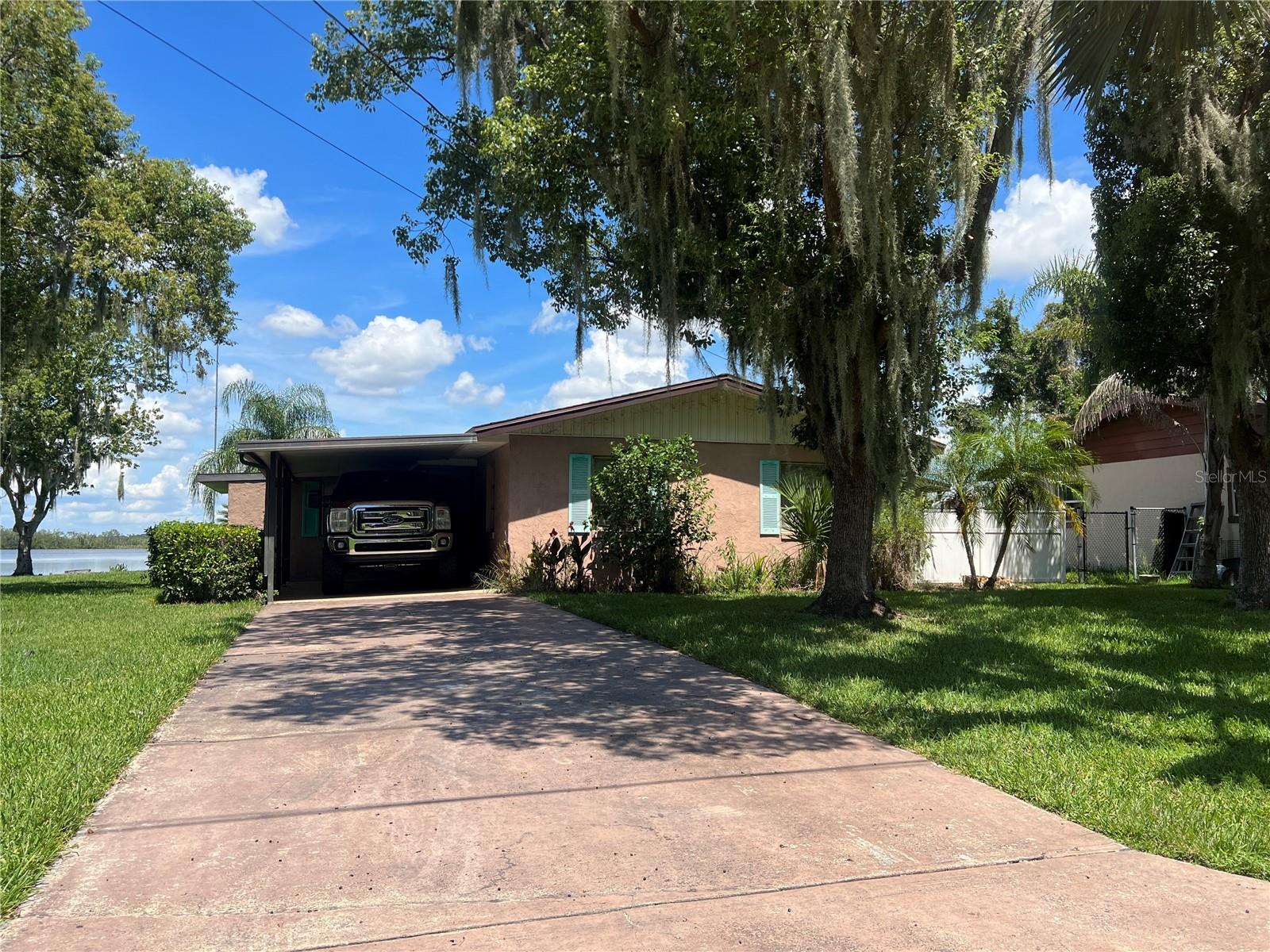Enjoy lakefront living with this unique waterfront property featuring both a canal in the front and lake access in the back. This 3-bedroom, 2-bathroom home offers approximately 1,400 square feet of living space and boasts a solid foundation with several major updates already completed, including a brand new air conditioner and a roof that's just 6–7 years old. Outdoor enthusiasts will appreciate the newer covered boat lift located at the front canal, along with a private dock at the rear for direct lake access. A spacious, covered back patio provides the perfect spot for relaxing or entertaining and includes a hot tub that stays with the property. With some minor cosmetic updates this is a fantastic opportunity to create your dream lakefront retreat.