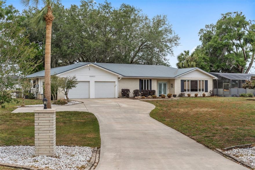 Welcome to Leesburg, the “City of Lakes,” where space, privacy, and convenience come together on this nearly one-acre homesite just minutes from Lake Silver and the Harris Chain of Lakes. This solid concrete block home offers a flexible split floor plan with two primary suites featuring private ensuites, plus an additional bedroom and bathroom, ideal for multi-generational living or guests. The updated kitchen with newer cabinetry and granite countertops opens seamlessly to a spacious living and entertaining area with a wood-burning fireplace and built-in bar, all connecting to a bright enclosed sunroom and pool area for easy indoor-outdoor living. A separate oversized living room with large windows brings in abundant natural light and adds even more functional space. Outside, enjoy mature oak trees, a large private pool with a recently replaced pump (2025), and plenty of yard space to relax or entertain. The property also features an oversized driveway with ample parking, a two-car garage, and no HOA, giving you flexibility and room for additional vehicles. Major upgrades include a metal roof installed in 2019 with a lifetime warranty, a newer drainfield, and a fully connected natural gas whole-home generator for reliable backup power. This is a well-maintained property offering land, upgrades, and a peaceful setting just minutes from everything Leesburg has to offer.