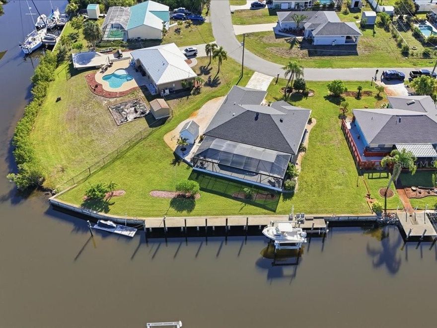 BOATER’S PARADISE!  This lovely home Truly is made for those who want the Florida boating lifestyle. Situated on an oversize lot at intersecting waterways with a turning basin, this home offers Approx. 177’ of concrete seawall, 87’ of concrete dock space with extra pilings, a 10,000lbs boat lift, water, electric, additional floating dock for jet ski and sailboat access to the Gulf (approx. 25 mins. to Harbor and 10 miles to Gulf).  At just under 1800sqft, this home features a large great room with vaulted ceilings, new wood look tile floors, designer ceiling fans, formal dining area, plant shelf and sliders to the lanai with views of the pool and waterway beyond.  The Eat – In - Kitchen features Laminate cabinetry and counters, (all appliances stay), new wood look tile floors, a dinette area with water views and sliders to the lanai.  The large primary suite features slider to the lanai, walk in closet, linen closet, carpeting and an en-suite bath with double sinks and a shower. A split floor plan includes Two additional bedrooms and a guest bath.   Both bedrooms have carpet, ceiling fans, and wood shutters.  A large laundry rm with included washer and dryer completes the interior of the home.  The Lanai area features recently installed pavers, ceiling fans, a pool bath, storage closet, out-door shower and accordion storm shutters. The newly renovated pool features a Huge 24X52 paver deck area, new pump, new heater, and new screen cage featuring “Super Screen” for unobstructed views of the water. (ALL done since 2020) 
Home features and upgrades include : New Roof(2020), New AC(2021), New Cage(2024), New Impact rated windows throughout(2025) New wood look tile floors throughout main living areas(2025),Upgraded ceiling fans w/LED lighting in bedrooms,  Pool Resurface(2025), New pavers in lanai and pool area(2025), Irrigation system with well, Screened front entry, 8X10 Storage shed, Stone extra parking pad, Dusk to Dawn LED lighting at dock, Dock wired for future 50amp (250V) elec. Svc. And Beautiful sunset views!
This Home has it all, definitely a must see!