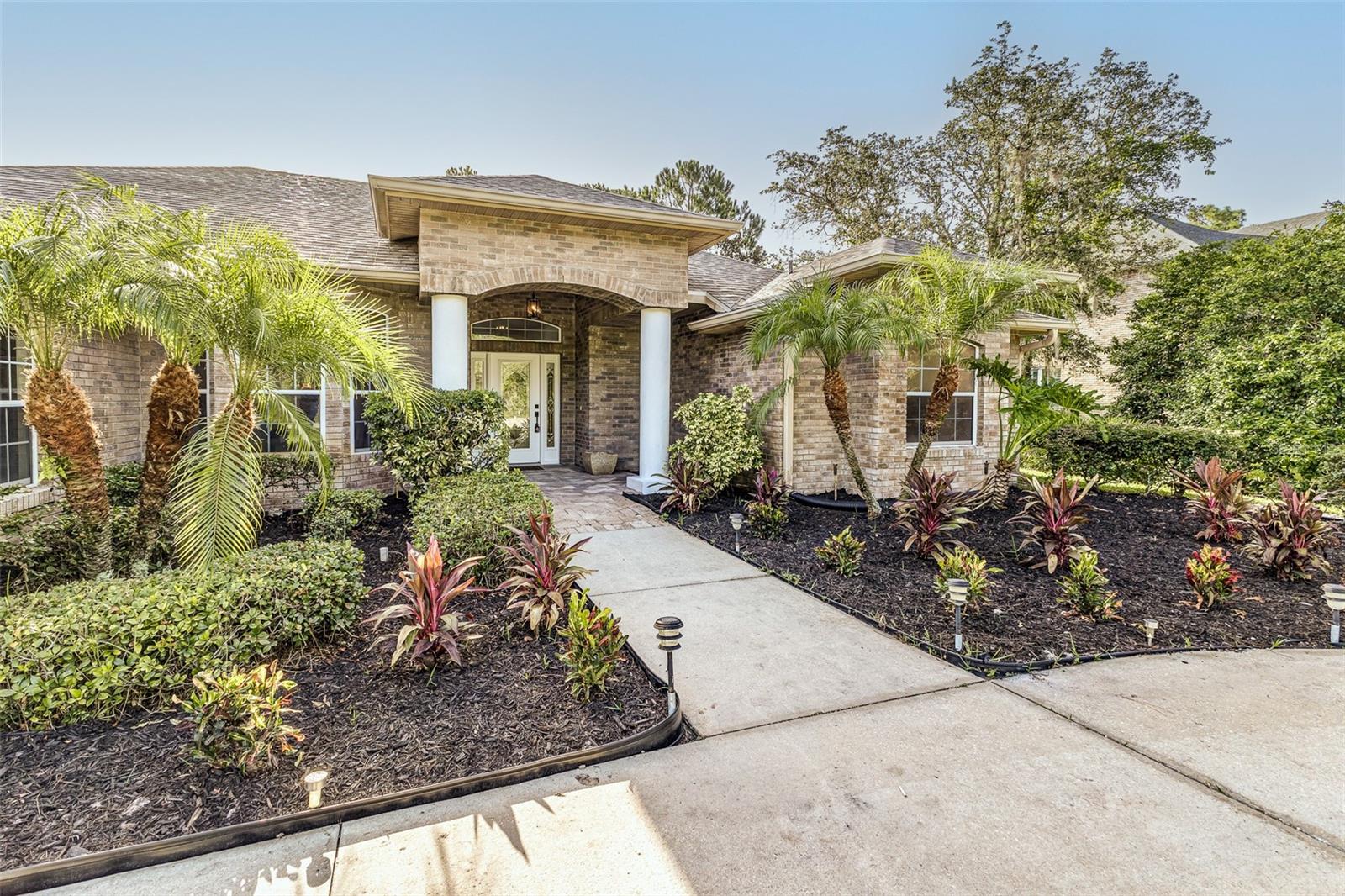 Welcome to the highly sought-after, gated community of Winnemissett Oaks—where estate-sized lots, mature oaks, and privacy meet convenience and elegance. This beautifully remodeled home sits on a sprawling 2.5-acre lot, situated at the end of a quiet, dead-end street, offering exceptional privacy with no rear neighbors and no neighbors to the left.
Thoughtfully upgraded throughout, the home features a new roof, new A/C, and stylish recessed lighting that highlights the clean, modern design. Soaring vaulted ceilings create an airy feel, and new flooring, fresh interior paint, updated baseboards, and modern fixtures complete the transformation.
The thoughtfully designed kitchen is a dream for entertaining, with all-new appliances, brand-new cabinetry, and a spacious island with barstool seating that flows seamlessly into the open living area.
The luxurious primary suite includes two walk-in closets with custom built-ins and a spa-inspired bath featuring a stand-alone soaking tub, frameless glass shower, gold fixtures, modern mirrors, and elegant tilework. The second and third bedrooms share a Jack-and-Jill en suite, while the fourth bedroom offers dual closets and a private full bath—ideal for guests or multi-generational living.
Additional features include an indoor laundry room with washer, dryer, and utility sink, and an outdoor wash basin for added convenience. The inviting pool area features a sun shelf and water fountain feature, creating the perfect setting to relax or entertain.
All of this is located just minutes from downtown DeLand, shopping, dining, and with easy access to I-4 and State Road 44, offering the perfect combination of peaceful living and everyday convenience.
