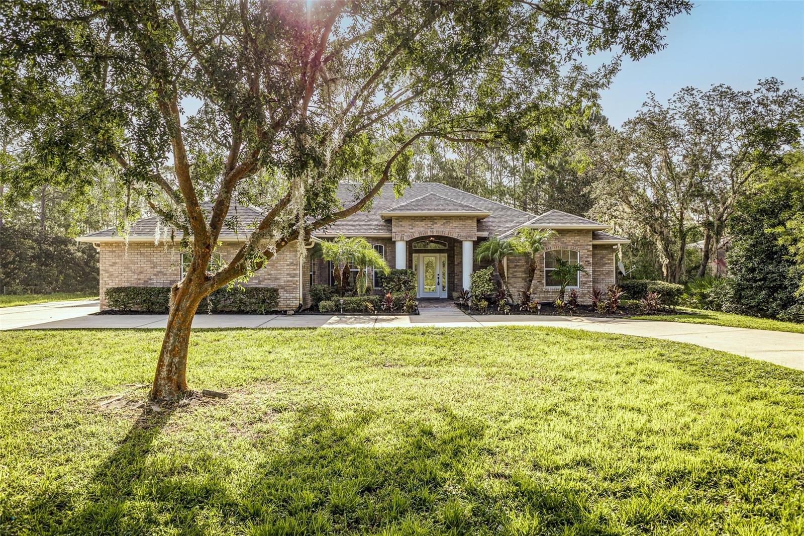 Welcome to the highly sought-after, gated community of Winnemissett Oaks—where estate-sized lots, mature oaks, and privacy meet convenience and elegance. This beautifully remodeled home sits on a sprawling 2.5-acre lot, situated at the end of a quiet, dead-end street, offering exceptional privacy with no rear neighbors and no neighbors to the left.
Thoughtfully upgraded throughout, the home features a new roof, new A/C, and stylish recessed lighting that highlights the clean, modern design. Soaring vaulted ceilings create an airy feel, and new flooring, fresh interior paint, updated baseboards, and modern fixtures complete the transformation.
The thoughtfully designed kitchen is a dream for entertaining, with all-new appliances, brand-new cabinetry, and a spacious island with barstool seating that flows seamlessly into the open living area.
The luxurious primary suite includes two walk-in closets with custom built-ins and a spa-inspired bath featuring a stand-alone soaking tub, frameless glass shower, gold fixtures, modern mirrors, and elegant tilework. The second and third bedrooms share a Jack-and-Jill en suite, while the fourth bedroom offers dual closets and a private full bath—ideal for guests or multi-generational living.
Additional features include an indoor laundry room with washer, dryer, and utility sink, and an outdoor wash basin for added convenience. The inviting pool area features a sun shelf and water fountain feature, creating the perfect setting to relax or entertain.
All of this is located just minutes from downtown DeLand, shopping, dining, and with easy access to I-4 and State Road 44, offering the perfect combination of peaceful living and everyday convenience.