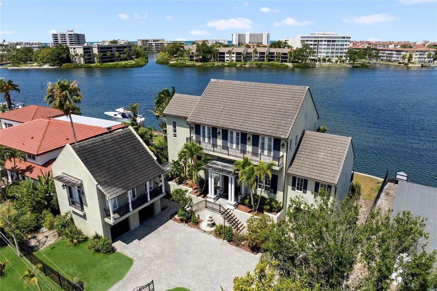 Welcome to Coucher du Soleil — French for "Sunset" — a magnificent gated waterfront estate styled after the grand French residences of New Orleans. Breathtaking views of Little Sarasota Bay, Siesta Key, and spectacular daily sunsets greet you from every room of this one-of-a-kind home. Impeccable craftsmanship is evident throughout, from the custom sapele mahogany front doors and hand-carved fireplace mantel to the handmade crown moldings and exotic sucupira hardwood floors. An elevator, exquisite lighting fixtures, exterior gas lanterns, and thoughtful hardware selections make this residence as functional as it is beautiful. The open-concept living and dining room flows seamlessly through numerous French doors onto an expansive covered balcony, also accessible from the guest suite and solarium. A custom library offers a tranquil retreat, while the entire top floor is dedicated to the primary suite, complete with a private office, morning kitchen, spacious dressing room, and private balcony with unsurpassed views. The carriage house provides an ideal in-law or guest suite with its own entrance, kitchen, bath, and balcony. Outdoors, enjoy the sprawling verandah overlooking the saltwater pool or head out on the water from your 50-foot composite dock with lift, electric, water, and sailboat access. Truly a one-of-a-kind Sarasota estate, do not miss this opportunity.
