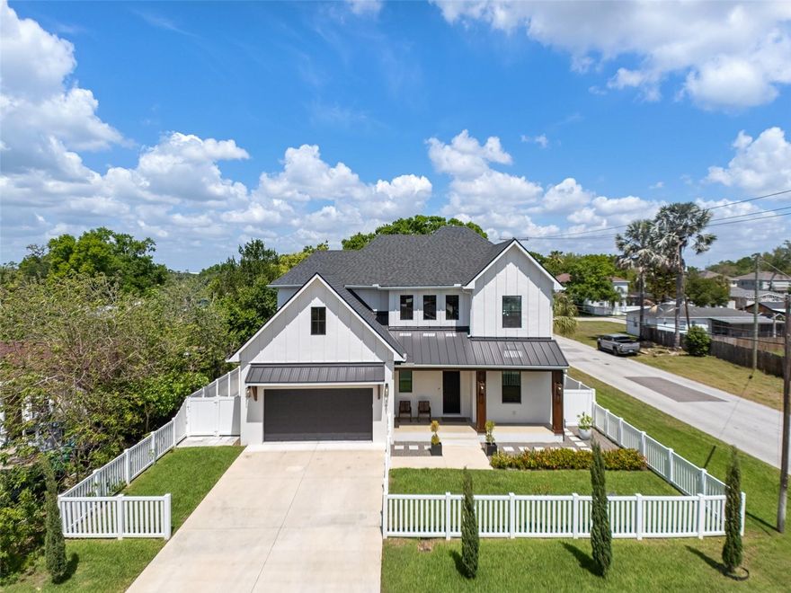 Curb appeal abounds with a classic white picket fence and a welcoming covered front porch accented by a subtle wood ceiling. Go through the 8-foot exterior doors into a breathtaking entryway with a soaring 22-foot foyer ceiling, setting the stage for the airy 10-foot ceilings and sleek luxury vinyl flooring that flow seamlessly throughout the five-bedroom layout. The meticulously designed interior is elevated by wood-framed doors, impact windows and striking metal railings for the stairs. The chef’s kitchen dazzles with gleaming quartz countertops, which are consistent throughout the home, a stunning art deco tile backsplash, and a high-end induction cooktop. Retreat to the luxurious primary suite, complete with thoughtfully built out dual closets and an en-suite bath with a frameless glass walk-in shower, split dual vanities and a separate deep soaking bathtub. The transition to outdoor living is effortless, enhanced by motorized shades on all rear-facing windows and doors. Outside, your private oasis awaits and gives way to a fully equipped outdoor kitchen boasting a grill, dual burners, a beverage refrigerator and a motorized retractable awning for ultimate climate control. The centerpiece of the backyard is a resort-style heated saltwater pool, complete with a tanning ledge and six-person spa, all enclosed in a tasteful cage with a turf area. Effortless living is guaranteed with a smart system controlling the pool and lighting, alongside added peace of mind of a pre-installed 50-amp generator hookup. Live the South Tampa lifestyle with quick access to the Selmon Expressway, St. Pete and Tampa International Airport, while only being a short distance from the iconic Bayshore Boulevard and downtown Tampa.
