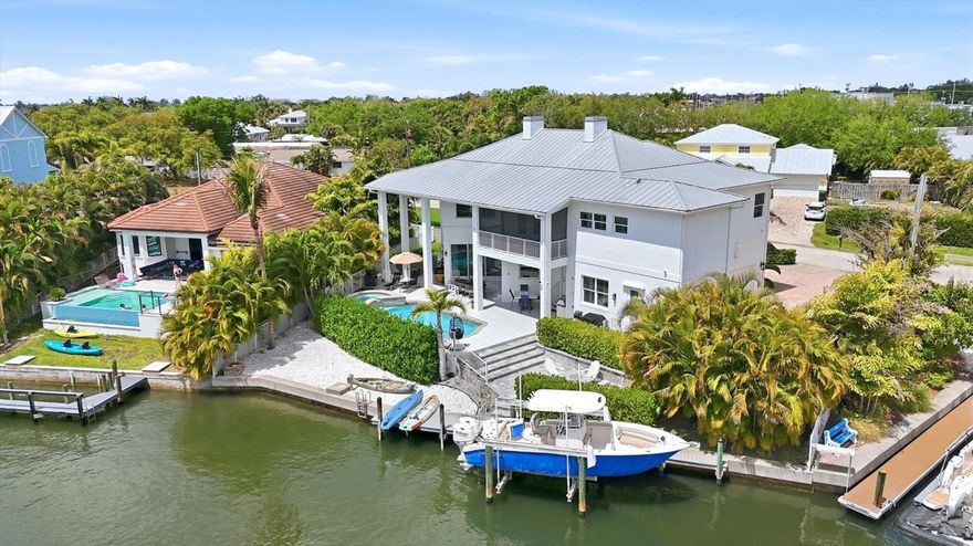 Resort-style waterfront living awaits in this beautifully appointed residence in Holiday Harbor, ideally positioned on a canal just moments from the Intracoastal Waterway. Designed for both effortless coastal living and entertaining, this 4-bedroom, 3.5-bath home offers an exceptional blend of space, functionality, and lifestyle-driven amenities.
Upon entry, soaring vaulted ceilings and an abundance of natural light create a bright, inviting atmosphere. The expansive living room, anchored by a gas fireplace, flows seamlessly into the dining area and recently renovated kitchen—perfectly oriented to capture views of the lushly landscaped pool and outdoor living spaces. The kitchen is thoughtfully designed for the culinary enthusiast, featuring extensive cabinetry, quality finishes, upscale appliances such as Sub zero, Bosch and Wolf and a generous walk-in pantry. Walls of windows in the dining area bring the outdoors in, enhancing the home’s light-filled, airy feel.
The first floor is designed for both everyday living and entertaining, offering a private office, laundry room, and a guest suite with en-suite bath and its own separate entrance—ideal for visitors or extended stays.
Upstairs, accessible by either a striking staircase or private elevator, the home continues to impress. Two guest bedrooms share a well-appointed Jack and Jill bath, while a spacious family room with wet bar and an additional media room provide flexible spaces for gathering and relaxation. The primary suite is a true retreat, featuring a private screened balcony with picturesque views down the canal toward the Intracoastal Waterway. The primary bath includes a soaking tub, separate tiled shower, dual vanities, and a large walk-in closet which also can accommodate a washer and dryer.
Step outside to your own private waterfront oasis. The heated saltwater pool and spa are complemented by multiple levels of outdoor decking—an upper level designed for poolside lounging, entertaining, and cooking out on the outside kitchen area. The lower deck is perfect for a fire table and evenings under the stars.
For boating enthusiasts, the property offers excellent canal frontage with quick, easy access to the Intracoastal and Gulf beyond—opening the door to endless days on the water, from sandbar outings and fishing to watersports and sunset cruises.
Ideally located near waterfront dining, top-rated schools, downtown Sarasota, and the world-renowned beaches of Siesta Key, this home captures the essence of Florida coastal living—where every day feels like a getaway.