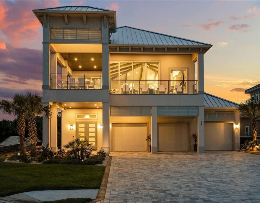 Coastal Modern luxury home in Ocean Hammock only one year young and better than new! Custom-built and thoughtfully designed with indoor/outdoor living in mind, this home provides just under 4,000 sq ft. of indoor living with almost 7,200 sq. ft. under roof, situated on a 0.4 acre lot and one of the largest in Ocean Hammock. The inverted floor plan with everything you need on the top floor allows you to take in the ocean views and breezes and is complete with elevator. Your guests will enjoy the spacious lower level with large entry foyer, 12 ft. ceilings, 3 guest bedrooms, 2 full bathrooms, a stackable laundry (no more carrying those beach towels upstairs!), drop zone with storage, and a central entertaining space with wet bar and built-in media center. Heading upstairs, the heart of this home is the expansive main living area with vaulted tongue/groove and wood beamed ceilings built with entertaining in mind.

The gourmet kitchen includes quartz countertops with waterfall island and full height backsplash, 48 inch Dacor range, 42 inch Dacor built-in refrigerator, island beverage center, Bosch dishwasher and microwave drawer. Double stacked cabinets with under and overmount lighting combined with additional cabinets on the front of island provide ample storage space. The open concept plan includes a large dining space suitable for your large gatherings, as well as the Family Room with built ins, open lighted shelving, and stacked stone electric linear fireplace. The gem of this area is the 16 ft. wide and 10 ft. tall zero corner slider which collapses to provide an extension of the living space to the wrap around southeast facing balcony with marine-grade railing system, perfect to take in those sunrises, ocean views, and rocket launches! Directly off this area is a wine room with lighted wine racks, a dry bar, and loads of built-in cabinetry. Sliding doors lead to yet another flex space - perfect for an additional home office, exercise/yoga room, or just additional seating - open up the balcony doors for the breeze! The primary bedroom is conveniently located on the upper living level, with custom cabinetry in the walk-in closet, en-suite bath with wet room tub and shower, dual vanities, linen cabinet and private access to the back sunset balcony - complete with stacked stone fireplace, mantle, TV and motorized screening. Rounding out the upper floor is a powder room, large laundry space, and a pocket office with custom cabinetry. Continue your coastal paradise outdoors, with an outdoor kitchen, outdoor shower, dedicated pool bath, and pool/beach storage room. The centerpiece of this backyard is the pool and 13 x 7 spa, with large sunshelf, fire/water bowls, and gas firepit, all surrounded by a fully fenced yard. Beach access is just steps away! This property is not in a flood zone so no required flood insurance. Other features include whole home automation including smart lighting, audio/visual, indoor/outdoor speakers, motorized shades and shutters, premium LVP flooring to withstand the sand and water, three-plus car garage with upgraded lighting, epoxy floors, pre-wire for electric vehicle, water softener, mini-split air conditioner in the third bay, and much more. Optional memberships to Hammock Beach resort are available. All TVs, audio/visual components, and washer/dryer remain and furnishings negotiable - all furniture is only 1 year old! Come live the coastal life of your dreams in this seaside sanctuary within Ocean Hammock!