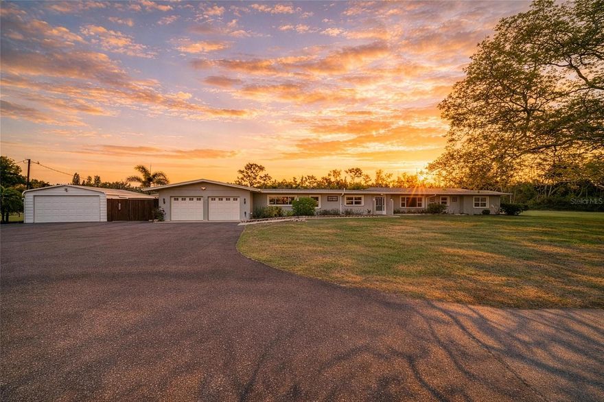 Invest in one of central Sarasota’s most versatile acreage opportunities with this gated 2.23-acre RE1-zoned estate offering rare land-use flexibility and no HOA or deed restrictions. Positioned for future growth, the property is fully secured with perimeter fencing and an electronic security gate at the 53rd Street entrance, with dual asphalt driveways already installed to support expanded use. A cleared and prepped secondary build site provides immediate potential for a detached guest house, ADU, additional garage structure, or professional-grade workshop. Approximately $100,000 in recent capital improvements—including a new roof, new water heater, heavy-duty double septic system with lift station, and extensive new asphalt paving—significantly reduce future infrastructure costs and strengthen the property’s development readiness. The existing block residence is dated yet fully functional, allowing for rental income, phased renovation, or redevelopment while long-term plans are executed. A four-car garage configuration includes an oversized attached two-car garage with workshop space and a detached air-conditioned two-car workshop, plus 50-amp RV hookups to accommodate commercial equipment, recreational vehicles, or specialty storage needs. The private pool and sand beach area enhance usability and short-term livability, all located just minutes from major retail, approximately five miles from UTC, and a short drive to downtown Sarasota. With infrastructure in place, zoning flexibility secured, and acreage becoming increasingly scarce in central Sarasota, this property represents a strategic land-bank, redevelopment, or custom compound opportunity with substantial upside potential. Schedule your private showing and evaluate the possibilities.