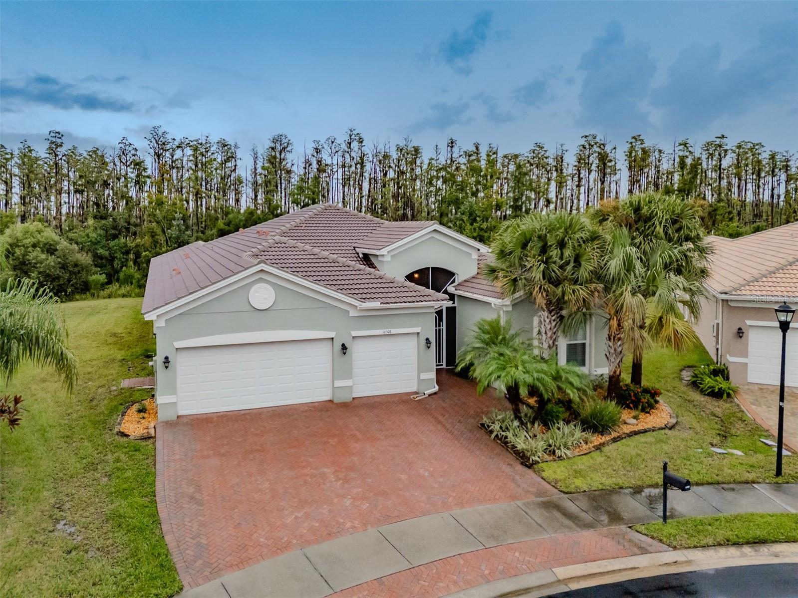 This 2,720SF GL Homes built Vizcaya has three bedrooms with ensuite bathrooms, an office, and an open floorplan featuring a great room, kitchen, dinette, dining room and a powder room. Enter through the screened-in portico with its 48” door that affords wide access and leads to the bold French double front doors. Inside the expansive foyer, take note of the towering 14’-15’ tray ceiling with its dazzling 7 pendant chandelier that will fashionably welcome family and friends. 18”x18” porcelain tile on the diagonal finished with large 5 1/4” baseboards grace the floors, and the walls meet the ceilings with custom crown molding. Right of the front door is the 3rd bedroom that features a walk-in closet, large windows with bespoke plantation shutters, a ceiling fan, and an ensuite bathroom highlighted by a walk-in shower with faux marble walls. Bedroom 2 has a beautiful ensuite bathroom, and a walk-in closet. The spacious primary bedroom is 19’x16’ with a 10’-11’ tray ceiling, and has a three-wall bay window facing a natural Cypress tree Preserve. Two generously sized walk-in closets with mirrored bi-fold doors flank the hallway leading to the ensuite. This ensuite features two separated vanities with quartz counters, a garden tub, a walk-in shower, a water closet for the commode, and a linen closet. An expansive great room anchors the Vizcaya’s open floorplan. A grand 10’-11’ tray ceiling with an extraordinary 14 blade 72” Monte Carlo ceiling fan and six recessed lights crowns the expansive 26’x20’ great room that also has a three-panel 12’ wide sliding glass door leading to the backyard oasis. The gourmet Chef’s kitchen features a breakfast bar, a center island, a double-basin sink with a reverse-osmosis faucet, espresso colored solid wood cabinetry with soft close drawers, lower cabinets with sliding shelves and pot drawers topped with quartz counters which in turn are accented by a stunning mosaic glass backsplash, stainless-steel appliances, a counter-cooktop with externally vented range hood, and wall-mounted double ovens. The kitchen has plenty of space for the Sous-Chef and basks in natural light. Adjoining the kitchen is a casual dining area overlooking the backyard oasis that will be the perfect space to enjoy daily or intimate meals. It also has an 8’ wide pantry with four levels of sliding shelves. A spacious formal dining room will comfortably host 10 persons. Windows in the common areas, the primary bedroom, and the second bedroom are adorned with a motorized Hunter-Douglas light filtering dual shades that have an additional third black-out shade as well. Discretely removed from the open floorplan is a powder room for visitors. The backyard oasis features 21’x10’ lanai, a 13’x27’ salt-water pool enclosed in a 34’x 25’ screen room, which is further enclosed by an aluminum picket fence. This is a perfect space to enjoy by yourself or share it with family and friends. The garage is big enough to accommodate 3 SUVs. It has epoxied floors, a walk-out door, insulated doors with belt-drive openers, wall mounted cabinets, a wall-mounted fan, and an additional outlet on a dedicated 20 AMP circuit. Environmental comforts are assured with a 4-ton HVAC, a 200 AMP electrical panel with an Eaton Complete Home Surge Protector, and all windows have hurricane resistant accordion shutters. Located in Valencia Lakes, Tampa Bay’s premier 55+ Active Adult community, this home is guaranteed to meet and exceed your needs.