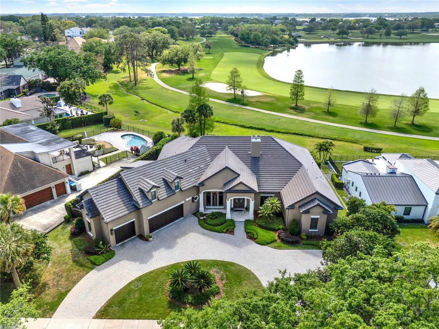 Located on Bay Hill's Championship course, overlooking the 3rd Fairway and one of the largest lakes in Bay Hill, this 5-bedroom, 4.5-bathroom home offers approximately 4,648 sq. ft. of living space on lush grounds with elegant architecture. The open layout is filled with natural light, featuring high-end finishes, elegant lighting, and high ceilings. The amazing kitchen includes an oversized breakfast bar, solid surface counters, Busby cabinetry, and built-in nook seating. The spacious great room boasts a fireplace, built-in sound, and multi-pocket sliders. The home also includes a large formal dining room, walk-in pantry, oversized built-in desk, and a large laundry room. The primary bedroom is a retreat, with a primary bath featuring two walk-in closets, a jetted tub, and a walk-in shower. A home office with Bamboo flooring and flexible guest bedrooms with ensuite bathrooms yields ample space. A bonus fifth bedroom or apartment above the garage includes a full bath and storage. The covered Lanai, with electric shades and built-in grill, stunning golf course and water views. A sparkling pool and spa with an elevated deck are perfect for relaxing. Built in 2009, this home is ideal for a luxurious lifestyle in Bay Hill, SW Orlando - Convenient & desirable Dr Philips area, A-RATED schools, close to shopping and attractions. Excellent value, won't last!