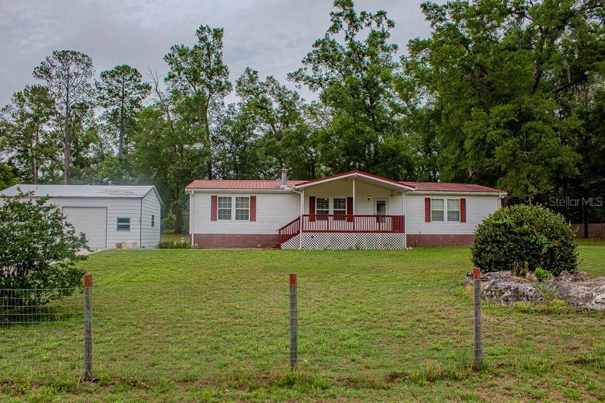 Peaceful Country Living Near High Springs! Nestled on just over an acre in the quiet community of Sherwood Forest, this well-maintained 3-bedroom, 2-bath double wide mobile home offers the perfect blend of comfort, privacy, and functionality. Fully fenced and equipped with well and septic, this property is ideal for those seeking space and freedom without HOA restrictions.
The home showcases true pride of ownership with a spacious layout, a large covered front porch perfect for relaxing, and a covered, enclosed rear porch that adds extra living or entertaining space. A handicap-accessible ramp at the rear of the home provides added convenience and accessibility.
Outside, you’ll find a detached block 2-car garage/workshop with one electric door—perfect for storage, hobbies, or projects. Located just outside of High Springs in Columbia County, this property offers a peaceful setting while remaining close to outdoor recreation, including O'Leno State Park. Enjoy small subdivision living with a quiet, tucked-away feel while still being convenient to town amenities.