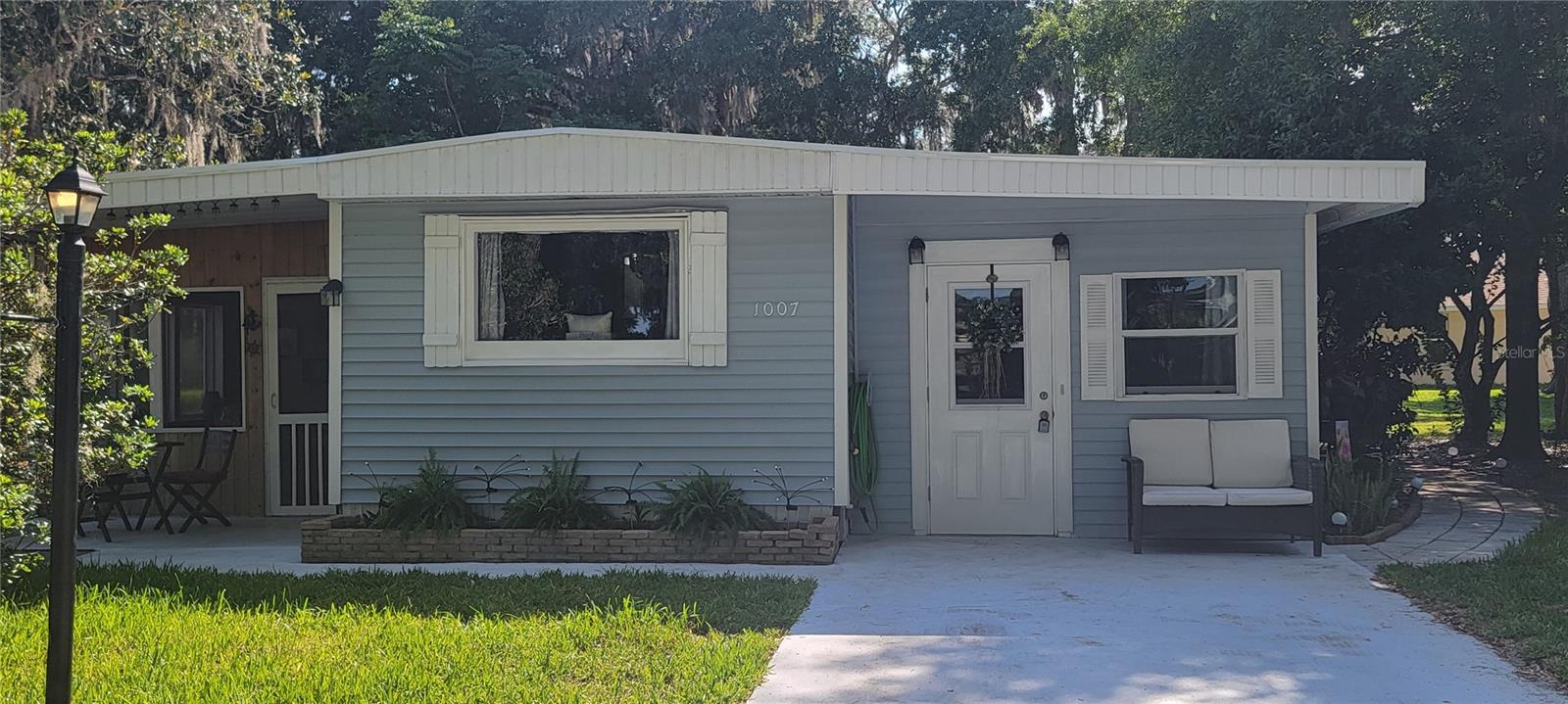 TURNKEY, NO BOND. Welcome to this wide open concept expanded single wide manufactured home in The Villages, nested among many oak trees, where little sunlight heats the property. Located in the Village of Orange Blossom, one of the most peaceful community in The Villages. This home features a true 13 x 12 woodworkers dream shop with its own AC, a large screened in lanai, 2 bedrooms and 2 baths. One bath has a tub and other has a walk in shower with seat. The large laundry room has cabinets and a large storage room with shelves and a Stand-up freezer. Home also has a bonus room that can be used for office, crafts, exercise, music, bar or even a 3rd bedroom with sliding doors that exit to the side seating area of its own. The kitchen features a kitchen island with power, plenty of cabinets for storage and a true extra large refrigerator and sink with aerator. Home also has a true large dining room and a comfortable living room as you enter the home. All plumbing has been replaced (no gray pipes), with most electrical updated, lots of dimmers & three way switches. Location of this home is ideal since its right off highway 441 full of restaurants, stores, entertainment and many services including medical centers and home improvement hardware stores.
The Villages is the most active city 55+ in Florida. Features all yr round golf with over 100 golf courses and community pools that also have hot tubs. Events here include but not limited to live music daily at our nearby squares, all kinds of clubs, classes and sports and hobbies that are endless!
INVESTOR: Here is an amazing opportunity to create an extraordinary experience for your short term rental portfolio!
Staging Decorations do not convey in this sale.
ROOF 2021, AC 2010, HWH 2007