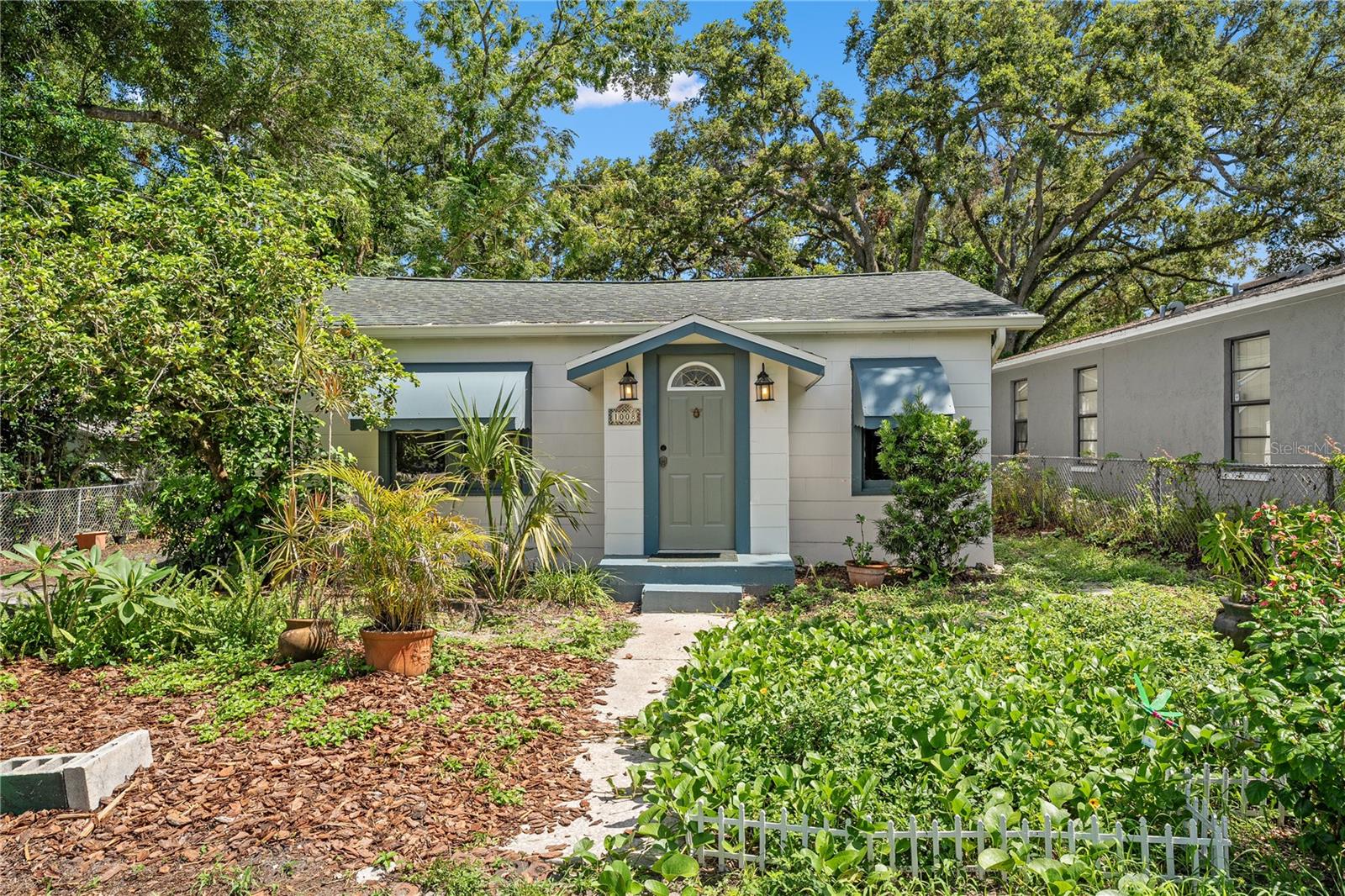 Located just two houses up from the river, this beautifully preserved 1949 home is full of original character and timeless charm. Gleaming original hardwood floors flow throughout the home, setting a warm and inviting tone from the moment you step inside.
Featuring two spacious master suites, this home offers comfort and flexibility. Need more space? A versatile den/office at the rear of the home could easily be converted into a third bedroom. The kitchen showcases classic wood cabinetry paired with brand-new appliances, blending vintage charm with modern convenience.
The back master suite includes a brand-new vanity and a stunningly tiled walk-in shower, creating a private retreat. Step outside to discover a generously sized lot with lush greenery, perfect for gardening, relaxing in the sun, or enjoying the shade. The large covered patio is ideal for entertaining or unwinding, and an oversized utility room offers excellent storage or the potential for additional living space.
Additional updates include newer electrical and a water heater that’s approximately five years old. Ideally located near major highways, Seminole Heights’ vibrant dining and entertainment scene, and everything else Tampa has to offer—this home is a rare find!