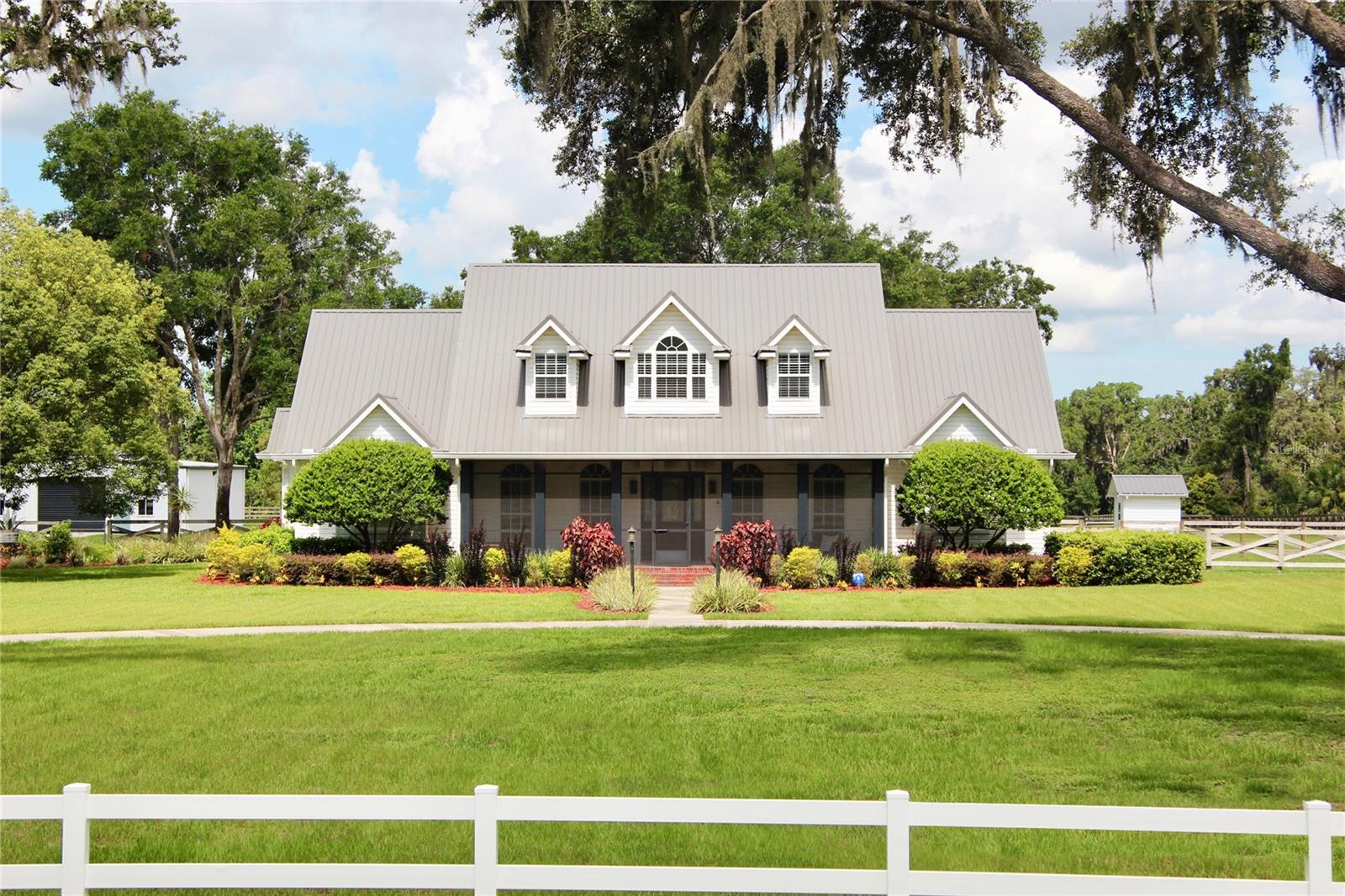 You will be sure to be overwhelmed when you drive up to this stunning custom-built estate that perfectly blends luxury, privacy, and functionality—nestled on nearly 6 acres just minutes from the coveted FishHawk community. Set behind a circular driveway and surrounded by majestic oak trees, this 5-bedroom, 4.5-bathroom pool home offers serene living with modern amenities. A charming screened front porch welcomes you into formal dining and office spaces with hardwood flooring and custom built-ins. The heart of the home is the beautifully renovated kitchen, boasting GE Café stainless steel appliances, a French-style oven, induction cooktop, convection microwave, walk-in pantry, and a reverse osmosis system. An elegant wine and coffee bar complements the expansive island that opens to the family room where you can cozy up by the electric fireplace or bask in the abundant natural light. Brand new custom shelving has been thoughtfully installed throughout the home, giving you both elegant display options and practical storage solutions that blend seamlessly with the home’s design.
The private primary suite features 2023 Duravana hybrid resilient flooring, a walk-in closet, and a spa-like en-suite with dual vanities, soaking tub, and separate shower. Two additional bedrooms with walk-in closets share a remodeled full bath, and the large laundry room includes built-in cabinetry. The upstairs was completely remodeled and offers a versatile loft, a full bath, a large storage closet with custom cabinetry and, two oversized bedrooms, providing a perfect retreat for teens or guests. French doors lead to a 2,100 sq ft screened-in oasis with a west-facing sunset view. Enjoy the 30’ x 18’ saltwater pool with a new 2023 salt system, pump, filter, LED lighting, and air-conditioned pool bath. Covered terraces provide shade and comfort for year-round enjoyment. The oversized two-car garage includes new built-in storage and attic space and connects to the home with covered walkways—perfect for rainy days. A brand new 2025 double carport with a matching metal roof adds additional sheltered parking. The fully fenced backyard includes a country-style wood fence and galvanized chain-link—safe for pets and ideal for gardening, animals, or play. A separate fenced dog run with doggy door access from the pool area adds convenience. Additional highlights include:
* 10-zone irrigation system.
* 2022 Tri County Metals roof (40-year warranty).
* 2023 well, softener, and Plentair pump in a dedicated shed.
* Whole-house generator in its own shed with switch panel.
* Smart alarm system with 10 cameras and 24/7 monitoring.
* Netgear Wi-Fi mesh system covering house and workshop.
* Solar-powered Ghost Controls gate for secure backyard access.
From 2023–2024, extensive landscaping improved safety and aesthetics, preserving the beauty of natural oak trees while enhancing low-maintenance lawns. At the rear, a fully insulated, alarmed, and freshly painted metal workshop features four oversized garage doors, a brand new full kitchen, A/C, refrigerator/freezer room, laundry with filtration, screened lanai, and full bath with hot water and RV hookup. A separate workshop and storage platform houses tools and can accommodate RVs up to 33 feet. This extraordinary estate is more than a home—it’s a lifestyle. Schedule your private showing today to experience its peace, privacy, and endless potential.