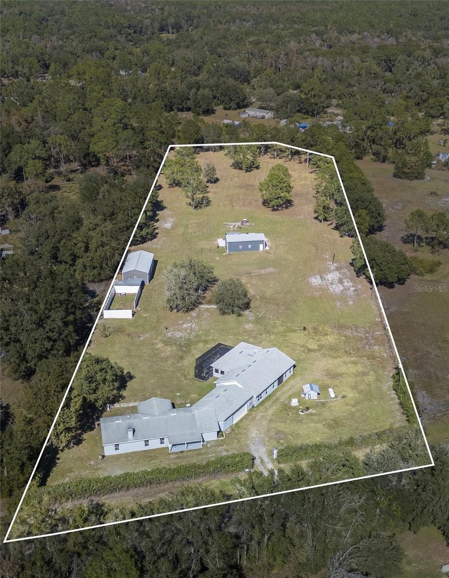 Rare 5-Acre Multi-Generational Retreat Just Minutes from I-4! Experience the perfect balance of modern living and peaceful country charm on this exceptional property featuring two move-in-ready homes seamlessly connected by a shared 2-car garage. The 2022-built primary home offers 2,109 sq. ft. of bright, open living space with a split floor plan, 2 bedrooms, and 2.5 bathrooms—perfect for entertaining and everyday comfort. The chef’s kitchen shines with custom cabinetry and granite countertops, opening to expansive living areas and a large screened lanai with brick pavers overlooking tranquil acreage. Abundant storage, a two-zone A/C system, and an additional side carport add to the home’s convenience and appeal. The updated secondary home (ADU or mother-in-law suite) provides an impressive 2,038 sq. ft. with a full kitchen, 3 bedrooms, and 3 bathrooms. The spacious primary suite features two separate bathrooms, including one with a soaking tub and separate shower. A versatile flex room can serve as a den, office, or additional storage, while a large rear porch creates yet another space to relax or entertain guests. This property is built for both function and fun, boasting an automatic front gate, 24k generator, owned 500-gallon propane tank, commercial-grade saltwater filtration system, A/C-controlled metal-roof barn (25x40), large tractor workshop (52x25), updated septic and drain field (2023), and a new well and pressure tank (2025). Whether you’re hosting gatherings, storing toys, hobby farming, or simply enjoying wide-open space and privacy, this one-of-a-kind property delivers unmatched flexibility and lifestyle appeal. Bring your toys, bring the dreams, and schedule your private showing today!