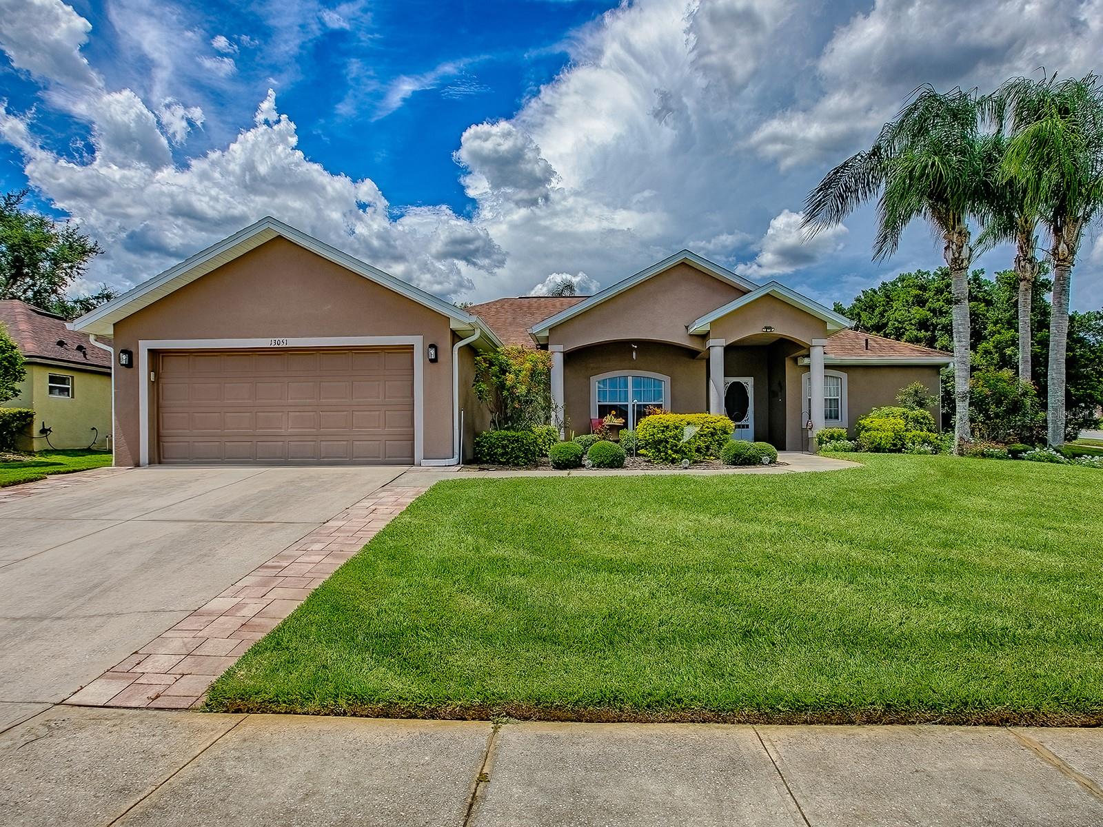 Welcome to your own piece of paradise, perched amid the rolling hills and tranquil lakes of Clermont. This beautifully maintained 3-bedroom, 2-bathroom home is ideally situated on a spacious corner lot adorned with lush, mature landscaping, offering a perfect blend of natural beauty, privacy, and convenience. You’ll love the unbeatable location: just 20 minutes to Disney and Orlando’s world-famous theme parks, and close to top-rated schools, shopping centers, restaurants, and everything the area has to offer, yet you’ll feel miles away from the hustle and bustle in this peaceful, established neighborhood. As you step inside you’re welcomed by the bright and airy living, dining, and Florida rooms, all showcasing views of the beautifully landscaped backyard. New laminate flooring in the living room, dining area, and primary bedroom adds a fresh and modern touch to the warm and inviting layout. The lovely kitchen features wood cabinetry, a breakfast bar, and breakfast nook and has a gas line already in place for those who prefer cooking with gas. The primary suite offers a peaceful retreat with a walk-in closet, additional coat closet, and an ensuite bathroom featuring dual vanities, a soaking garden tub, and a stunning new custom shower. The ideal split floor plan provides two additional bedrooms, both with walk-in closets, and a spacious second bathroom. The oversized laundry room has tons of space and storage, while the air-conditioned garage with custom-painted floors and an insulated, rebuilt garage door (with lifetime warranty) adds endless possibilities; perfect as a game room, workshop, or traditional garage. Adding to the appeal of this impressive home is the Florida room, which provides additional living space and panoramic views of your private, landscaped backyard sanctuary. Step outside to a paver patio and tree-shaded sitting area, ideal for relaxing mornings or quiet evenings. A paver sidewalk wraps around the home, enhancing the home's charm and functionality. All of this plus, the added reassurance of a new A/C system installed in 2023 and a roof that's just 8 years old. Peaceful, private, and perfectly located…this Clermont gem is ready for you to move right in!