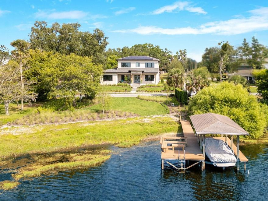 Completed New Construction 2024 | Lakefront Luxury | Below Appraised Value: This extraordinary custom lakefront residence was built by Dave Konkol & is elevated on a 0.56-acre corner lot w/ approximately 112’ of lake frontage. Featuring a crisp stucco exterior, impact windows & remote-operated screened porches, the home is surrounded by professionally designed native landscaping & butterfly gardens which set the stage for a lifestyle defined by natural beauty, enduring materials, timeless design & everyday comfort. Once inside, the open floor plan showcases wide-plank, white oak engineered wood flooring & is filled w/ natural light from the large format windows that frame views of the backyard pool & serene Lake Sybelia out front. A formal dining space connects to a wet bar & opens to a functional yet casually elegant kitchen. Quartz countertops, custom soft-close cabinetry with pull-outs & a full suite of premium appliances lend functionality & refinement to the kitchen. A large walk-in pantry & adjacent drop zone add quality of life to the beautifully tailored design. The main-level primary suite is a sanctuary w/ lake views, remote-controlled blackout shades, decorative wood ceiling beams, a customized walk-in closet & a spa-like bathroom featuring Frank Lloyd Wright Brizo plumbing fixtures, a long vanity stained to match the fixtures, dual sinks, an oversized glass-enclosed shower with 21” rainhead, soaking tub & private water closet. A guest bedroom w/ adjacent full bath also functions as a pool and powder bath. The large laundry room w/ quartz countertops, GE Profile front-loading washer and dryer & a Laundry Jet Swift pneumatic laundry chute—connected to the primary suite & upstairs bedrooms and complete the main floor. Upstairs, two additional bedrooms with wide water views include customized closets & designer baths. The cozy loft and Bonus spaces flex easily for work, wellness, or play. Other interior features include built-in speakers, custom millwork, motorized blinds & smart-home wiring to enhance comfort and livability. Seamless indoor-outdoor transitions define the rear living experience, where a deep covered lanai includes recessed lighting, fans, speakers & motorized screens opening to a 7’ deep, heated, saltwater pool w/ sunshelf, outdoor shower & direct access to a full bathroom. The fenced backyard offers ample space for play, relaxation & a dog run. A custom dock w/ composite decking & covered boat lift sits on Lake Sybelia—offering year-round opportunities for boating, paddle-boarding, swimming & fishing on waters with no public access. Efficiency abounds thanks to a PES Solar system featuring 58 REC panels, four Enphase battery backups & real-time energy monitoring. Additional features include Trane HVAC systems, a commercial-grade water heater w/ recirculating pump & a new irrigation system w/ pump fed by lake water. The three-car garage includes modern paneled doors w/ openers and extra storage. Now unexpectedly available due to a change in the owners’ plans, this is a rare opportunity to purchase an almost-new custom home—combining advanced systems with timeless design—in one of Maitland’s most beloved neighborhoods, just minutes from Lake Lily Park, downtown Maitland, major thoroughfares and Winter Park’s shops and restaurants.