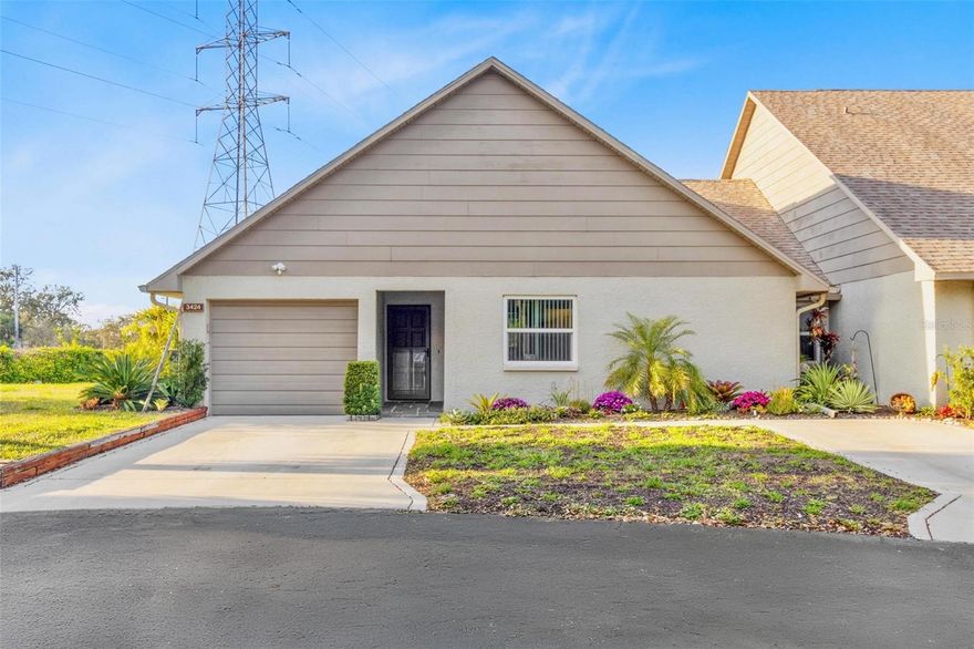 Discover this exceptional turnkey villa style condo, situated in a NON-FLOOD ZONE and providing access to a community swimming pool, offering both privacy and convenience. This inviting 3 bedroom, 2 bath corner unit villa features a 1 car garage with newly paved, two private parking spaces, and a sidewalk. The property boasts desirable upgrades, including renovated bathrooms, upgraded flooring throughout, a new water heater, and a new AC system. The kitchen is equipped with stainless steel appliances, a brand-new refrigerator, and stone countertops, complemented by an adjacent cozy eating area that connects with beautiful french doors to a large, sunlit screened-in Florida room. The impeccable landscaping enhances the curb appeal and provides a serene outdoor space. Don't miss this fantastic opportunity in an unbeatable location, just a few miles from Countryside Mall, shopping, dining, and minutes to Downtown Dunedin, and Honeymoon Island state park and beaches.