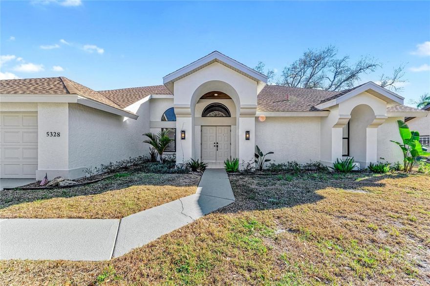 Fully reimagined with intention and thoughtful design, this spacious pool home offers a rare combination of architectural character and modern updates within a quiet, established neighborhood setting. Step through the double front doors into an expansive living and dining great room where soaring vaulted ceilings and arched transom windows create an immediate sense of light and openness. This welcoming space sets the tone for the entire home - airy, elevated, and designed for gathering. From there, the layout flows seamlessly into the kitchen and family room, creating a natural connection between entertaining and everyday living. The kitchen features granite countertops, shaker cabinetry, a statement hood, and an oversized island wrapped in vertical fluted wood detailing that adds warmth and architectural interest. Above, a recessed tray ceiling with inset panel accents enhances the custom feel of the space. The adjoining family room is anchored by a striking fireplace feature wall finished in painted horizontal shiplap and complemented by custom built-in shelving. Multiple sliding glass doors extend the living space directly to the screened lanai and sparkling pool, creating the perfect Florida lifestyle setting. Indoor and outdoor living blend effortlessly, whether hosting friends, enjoying family time, or relaxing poolside under the covered patio. The primary suite serves as a private retreat with direct lanai access, generous proportions, and a spa-inspired bathroom featuring a frameless glass walk-in shower, soaking tub, and spacious walk-in closet with abundant storage. Secondary bedrooms are well-sized and thoughtfully arranged, offering flexibility for guests, family, or a dedicated office. Spacious, light-filled, and designed for effortless indoor-outdoor living, this is the kind of home that simply feels right the moment you walk in. Designed for connection, comfort, and the best of Florida living, this is the complete package. Homes with this level of volume, privacy, and thoughtful renovation do not stay available for long. Schedule your private showing and experience it for yourself.