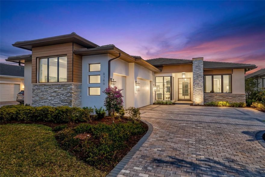 Under contract-accepting backup offers. Stunning Award-Winning Former Model Home – Better than new, turnkey furnished, and no waiting.
This exceptional residence is a must-see for those seeking elevated luxury and thoughtful design. As a former model home (with over $150K in additional after closing improvements), this property showcases premium upgrades and architectural details throughout, blending modern transitional style with warm wood tones, custom tile work, and designer finishes. Step through the striking crackled glass & iron pivot front door into a grand marble foyer featuring custom moldings, exquisite ceiling details, and elegant lighting that sets the tone for the impeccable craftsmanship found everywhere. Highlights include a dramatic fluted wood feature wall with a linear fireplace, custom ceiling treatments with cove lighting, a hidden walk-in pantry with custom built-ins, and a boutique-style owner’s closet that feels like a dream. The gourmet kitchen is a chef’s paradise, complete with upgraded professional appliances, a stunning waterfall island, and an expansive walk-in pantry designed for both beauty and ultimate organization. Sun-drenched and serene, the outdoor living space is truly breathtaking. Enjoy unobstructed, sweeping views of nature from an inviting lap pool, custom pool deck, and fully equipped outdoor kitchen — all protected by StormSmart storm screens. The pool bath features floor-to-ceiling decorative tilework for a spa-like touch. A show-stopping wrap-around glass wall with sun shades floods the home with natural light while framing the peaceful surroundings. Additional luxury features include: Stunning window treatments throughout, with room-darkening draperies and shades. Versatile bonus room with pull-out sofa bed and built-in cabinetry. Dedicated office with custom moldings and thoughtful built-ins. Control-4 home automation and whole-home sound system. Landscape lighting, newer epoxy garage floor, and freshly painted interior (including the garage) Better than new and fully furnished, this lock-and-leave home exudes sophistication and tranquility in every detail. Located in Wild Blue, one of Lakewood Ranch’s most desirable new luxury enclaves, residents enjoy resort-style amenities including tennis and pickleball courts, a restaurant and bar, state-of-the-art fitness center, golf simulator, and more. The location is incredibly convenient — just minutes from shopping and dining at Waterside Place and University Town Center. This is truly a rare opportunity to own a turnkey, move-in-ready luxury home in a premier community. Your dream lifestyle awaits!