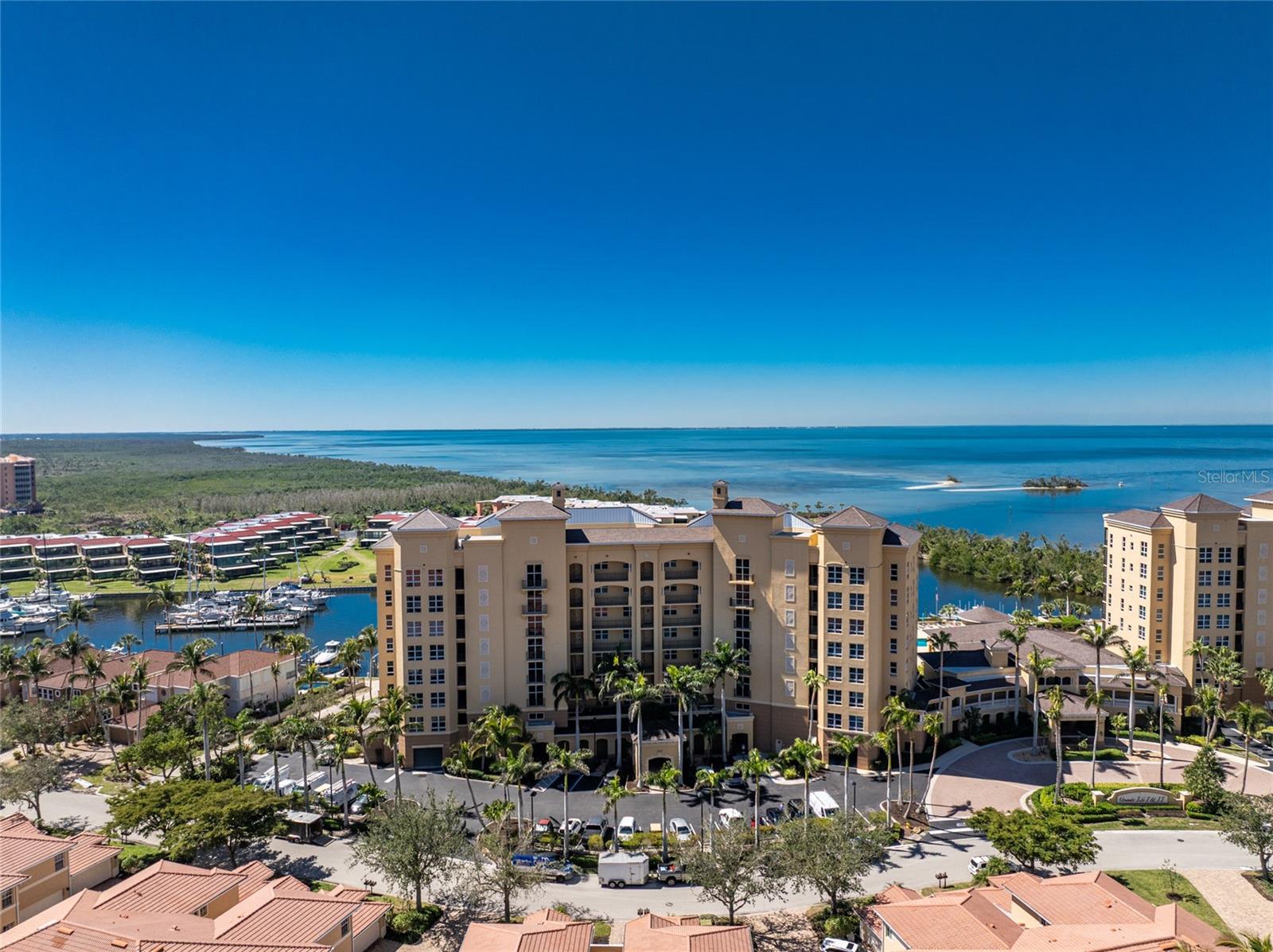 Exceptional opportunity awaits for luxurious waterfront living in this updated, rarely available end-unit penthouse in Grand Isle Towers. Perfectly positioned on the south end of the top floor with direct views of the marina channel entrance, Charlotte Harbor and the south marina basin. You will not only enjoy colorful Florida sunsets from your tiled and screened lanai, but also from many rooms inside. Pleasing volume ceilings and walls of glass help to flood the space of this FULLY FURNISHED residence with natural light, offering panoramic water views from nearly every room. The tiled, open-concept living area showcases spectacular views of Charlotte Harbor and boats sailing in and out of the marina’s main channel and is anchored by a striking custom built-in feature wall, complete with handsome illuminated wood display shelving mounted on ship lap and custom recessed accent lighting. A sprawling quartz surface tops off custom Amish cabinet and drawer storage with goldtone hardware—creating a stylish and functional focal point. The bright open kitchen makes entertaining a pleasure, featuring a large breakfast bar, abundant cabinets with expansive granite tops, and Whirlpool stainless steel appliances. Adjacent to the kitchen, a beautifully designed entertainment bar adds a touch of elegance with custom Amish navy blue cabinetry with gold hardware, with quartz tops and backsplash, glass display cabinets, handy beverage refrigerator drawers, and a True ice maker—perfect for hosting guests in style. The updated primary suite is a private sanctuary, showcasing floor-to-ceiling windows and sliding doors that frame incredible views of the marina and harbor. You'll love the neutral wood plank tile flooring, walk-in closet with custom built-ins, and a spa-inspired customized primary bath featuring dual vanities with quartz countertops, abundant drawer storage, a dedicated cosmetic station, and updated frameless glass walk-in shower with eye-catching tile inlays. The guest wing offers optimal privacy and versatility with two guest bedrooms, and a spacious den with wood flooring. Both guest rooms have LVP flooring and offer views of the lush Sunset Key Lagoon and island pool, and one includes a beautifully appointed ensuite bath with a walk-in shower, custom freestanding vanity, framed mirror and California closet. Enjoy peace of mind, as your stunning views are framed by impact-rated glass doors and windows throughout, and protected by motorized hurricane roll-down shutters on the lanai for added peace of mind. Grand Isle boasts resort-like amenities, including a private fitness center, theater room, grand salon, and an expansive waterfront deck with an Olympic-size geo-thermal heated swimming pool, spa, and grilling area. Residents of Burnt Store Marina enjoy a vibrant recreational lifestyle, with two on-site restaurants, a 27-hole golf course, active pickleball & tennis groups, fitness center, and the largest deepwater marina in SWFL.