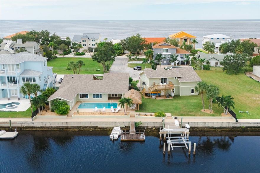 Waterfront living meets versatility and privacy at this exceptional New Port Richey waterfront estate with Gulf access, perfectly positioned on a rare double lot totaling 0.43 acres. Offering 4,018 square feet of living space, this unique property features a 3-bedroom, 2.5-bath main residence plus a detached 2-bedroom guest house, ideal for multi-generational living, guests, or rental opportunities. Originally restored in 2017, the main home showcases a chef’s kitchen with vaulted wood-beamed ceilings, granite countertops, stainless steel appliances, double ovens, and a spacious pantry. The expansive great room captures serene water views, creating the perfect setting for entertaining or relaxing. The primary suite is a private retreat, featuring French doors, a flexible bonus room currently used as a home gym, a spa-inspired bath with soaking tub, dual vanities, and custom California Closets. Step outside to your private waterfront oasis complete with an open-air saltwater pool, tiki hut with power and lighting, and a private dock with concrete pilings and a 16,000-lb boat lift, providing direct access to the water for boating and fishing enthusiasts. Car collectors, RV owners, and hobbyists will appreciate the impressive 45' x 38' detached garage with space for 4–6 vehicles and RV storage. Above the garage, a private two-bedroom guest suite with full kitchen, bath, and balcony overlooking the water offers exceptional flexibility. Additional highlights include 20 owned solar panels, solar water heater, plantation shutters, lush landscaping, and a two-car attached garage. This rare property delivers the ultimate Florida waterfront lifestyle for boaters, entertainers, and those seeking space, privacy, and flexibility—just minutes from downtown New Port Richey, waterfront dining, and the Gulf of Mexico.