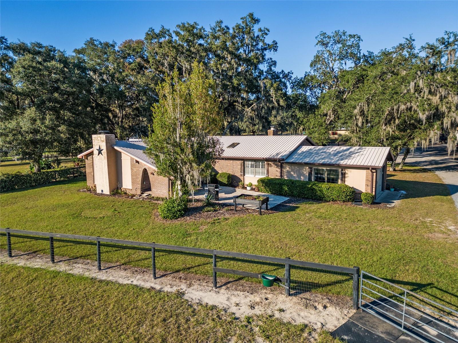 Experience the best of Ocala’s iconic horse country with this refined 10-acre offering, located less than half a mile from the World Equestrian Center and under 15 minutes to both HITS and Ocala Breeders Sales. Blending equestrian functionality with relaxed country elegance, this property presents a rare opportunity in one of the region’s most coveted locations. Fully fenced and gated for privacy and peace of mind, the land is framed by mature oaks and thoughtfully laid out with 14 board-and-wire paddocks, a well-groomed jump field, and a dedicated round pen. Two barns—offering a total of 12 stalls—are equipped with a wash rack, hot water, fly spray system, tack room, and feed room to support daily routines with ease. A spacious workshop and RV garage add further versatility for hands-on hobbies, storage, or extended-stay visitors. Also included is a covered RV with an attached deck, offering an additional inviting space for guests or farm help. A whole-home generator provides added peace of mind. At the heart of the property, a beautifully maintained 3-bedroom, 2-bath home offers over 2,000 square feet of inviting living space. Bamboo wood flooring flows throughout much of the home, complemented by porcelain tile in select areas. A cozy wood-burning fireplace and French doors in the living room open to the back patio, creating seamless indoor-outdoor connection. The kitchen is well-appointed with stainless steel appliances, a gas range, built-in wine rack, breakfast bar, and ample counter space. The expansive primary suite includes its own wood-burning fireplace, an oversized walk-in closet with built-in shelving, and a luxurious private bath complete with soaking tub, walk-in shower, and in-suite laundry. Outdoor living is just as inspired. A screen-enclosed pool area features a sparkling in-ground pool, shaded lounge area, and panoramic views of the surrounding farm. A raised porch with pergola offers a quiet perch above the jump field, while a shaded garden nook and front paver patio provide inviting spaces for gathering or relaxing. Blending thoughtful amenities with timeless charm, this property is an ideal base for active equestrians or those seeking a tranquil, well-appointed retreat. With infrastructure in place and a prime location, it’s ready for your horses, your vision, and your next chapter.