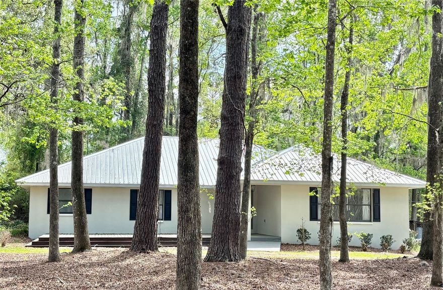 Truly beautiful multi-home estate on 5.5 private acres in Alachua! High-end, turn-key ready and immaculate, featuring four separate buildings: Main Residence, In-Law House, Office/Workshop, and Barn, all with durable metal roofs. Main Residence: 4 beds / 3.5 baths, 2,531 SF, concrete block, large open floor plan, chef’s kitchen with quartz countertops, island, custom pantry, KitchenAid appliances, apron sink, drawer microwave, 36” gas range, custom vent hood, dry scullery with full-size refrigerator space + lazy Susan. Dual suites with Master featuring jetted tub, double showers & sinks, large his-and-hers closets. Bonus: wine/wet bar and office/flex room. In-Law House: 2 beds / 1 bath, 800 SF, fully updated and private with brand new septic tank. Two-Story Office & Workshop: 576 SF per level; lower level finished workshop with porch, upper level private 2-bed / 0.5 bath office space with a peaceful wraparound porch. Outdoor oasis: 800 SF / 40,000-gallon in-ground pool surrounded by nature with brand-new deck and outdoor shower, two main residence decks, two pool decks with 550+ SF sunbathing space. Barn: 600 SF shed/barn with porch, ideal for hobby farming or equipment. Driveway, gates, and culvert are brand new. Pool needs resurfacing—seller offering credit at closing. Owner/Agent.