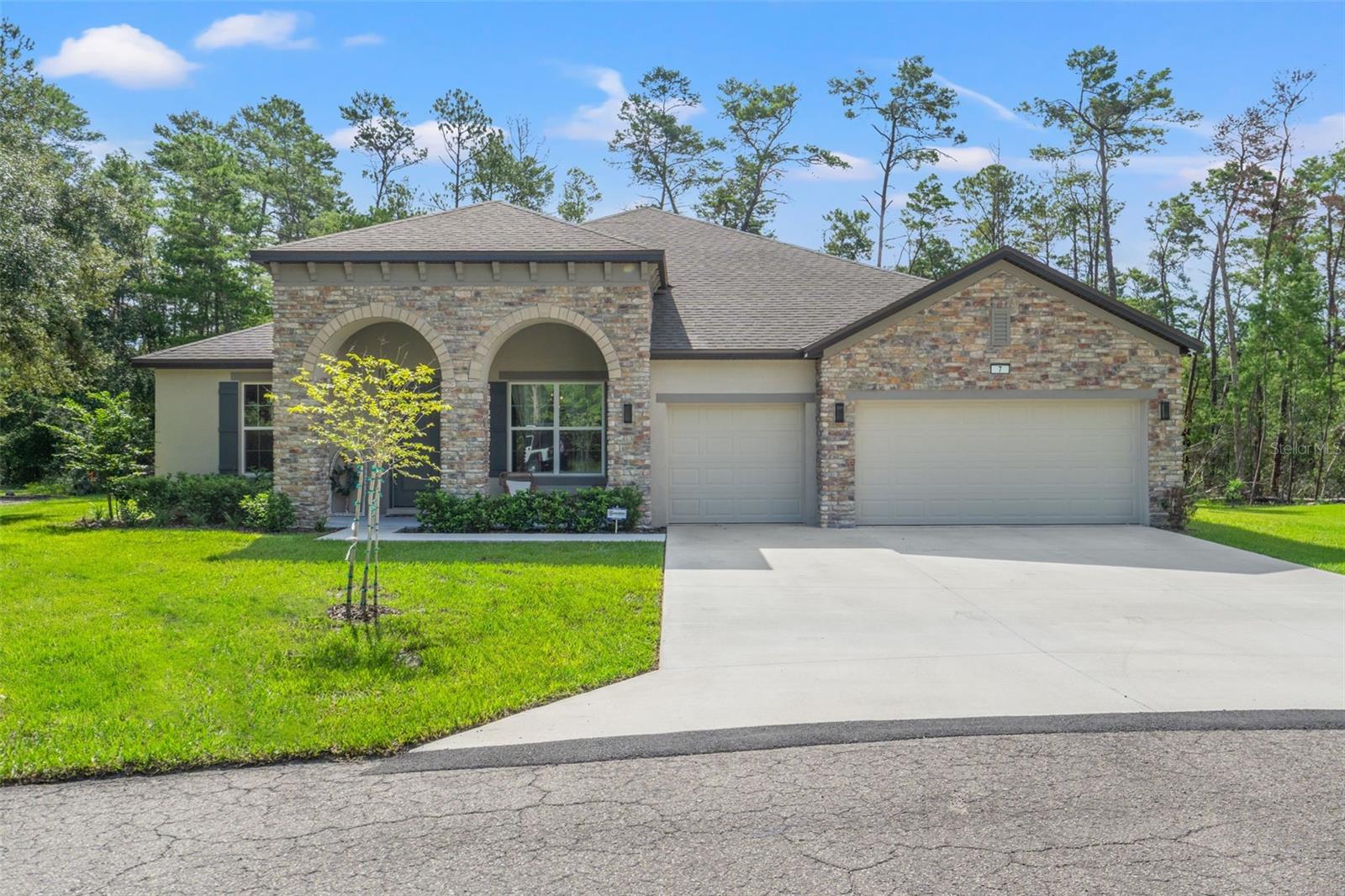 Exquisite 2024-Built Estate in Sugarmill Woods – Modern Luxury Meets Timeless Design, Meticulous and Contemporary; this custom-built 2024 residence is perfectly positioned on a private cul-de-sac in the highly sought-after community of Sugarmill Woods. Offering 3,029 square feet of living space (4,072 total), this move-in-ready masterpiece blends impeccable style with everyday comfort. The striking stone-accented façade, grand arched entryway, oversized driveway, and three-car garage set the stage for the elegance within. Inside, an expansive open floor plan unfolds beneath soaring tray ceilings and crown molding, with oversized windows and multi-sliding glass doors that flood the interiors with natural light. The great room is anchored by a striking custom marble-accent wall with an inset television and electric fireplace, seamlessly opening to the fully covered lanai—perfect for entertaining or simply enjoying the peaceful, wooded surroundings. Set on a greenbelt with the rear of the property backing to a protected nature preserve that can never be built on, the home offers unmatched privacy and serene views year-round. The chef’s kitchen is both beautiful and functional, featuring an oversized granite island with seating for six, full-height glass tile backsplash, premium stainless-steel appliances, two walk-in pantries, and designer pendant lighting. The adjacent dining area and open-concept layout make it an entertainer’s dream. The primary suite is a sanctuary, showcasing tray ceilings, abundant natural light, and a spa-inspired bathroom with dual granite vanities, an expansive walk-in shower with dual shower heads, and an oversized walk-in closet designed for maximum storage. The private mother-in-law suite is a standout, offering its own living room, wet bar with sink and wine refrigerator, abundant cabinetry, walk-in closet, and an en-suite bath with a glass-enclosed walk-in shower. Designed to age gracefully with its occupants, this space is adaptable for future needs—whether as a comfortable guest retreat, private studio, or even a home movie theater. Additional living space includes a versatile office/flex room with French doors, ideal for a study, bar, or playroom. The large laundry room boasts wall-to-wall cabinetry, granite counters, and a utility sink. Luxury vinyl plank flooring runs throughout, providing elegance with low-maintenance care, while custom door hardware and modern faucets add refined touches. Smart home features elevate daily living—you can control the thermostat, garage doors, washer, dryer, oven/range, and refrigerator directly from your phone. The property is also equipped with a Guardian Security System that includes a doorbell camera and two additional exterior cameras for peace of mind. For storm preparedness, a Generac whole-house automatic propane generator with an underground tank, installed in April 2025, ensures uninterrupted comfort. Residents of Sugarmill Woods have the option to enjoy an array of lifestyle amenities for an additional cost, including access to the country club, pool, and spa. No expense has been spared in crafting this exceptional home, which combines modern luxury, advanced technology, and timeless elegance in a private yet convenient location. Schedule your private tour today—this one will not last.