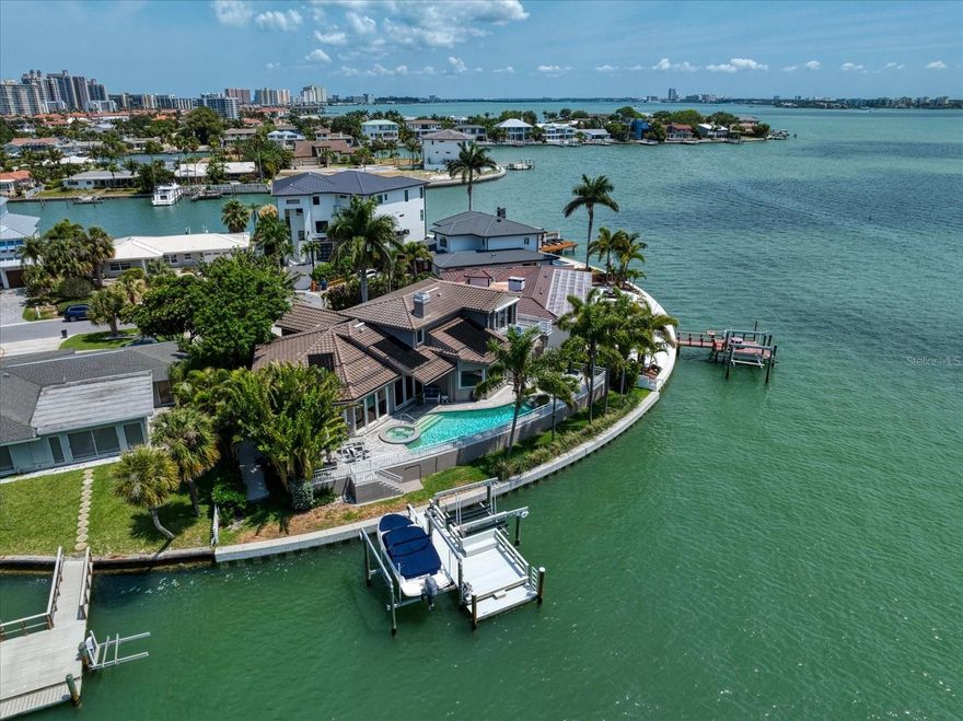 One or more photo(s) has been virtually staged. Positioned at the end of a cul-de-sac and framed by sweeping wide-water views, this exceptional waterfront residence offers a rare combination of architectural scale, thoughtful design, privacy and premier boating access. With 120 feet of seawall and a 30’ x 30’ dock, the property is ideally suited for boating enthusiasts, featuring a 10,000 lb. boat lift and a 6,000 lb. lift accommodating two jet skis, along with a grandfathered off-center dock placement that maximizes water access and views.

Built in 1992 and encompassing 3,406 square feet, the home offers three bedrooms, three full baths, and two half baths, with expansive living spaces designed to capture the surrounding water vistas from virtually every room. Rich hardwood floors extend throughout, complementing the impressive 33’ x 26’ living room and an expansive 30’ x 25’ kitchen and breakfast area designed for both everyday living and entertaining. The kitchen is equipped with three sinks and two dishwashers, while a climate-controlled wine cellar provides dedicated storage for a curated collection.

The first-floor primary suite offers comfort and privacy, while a spacious office with custom built-ins provides an ideal setting for work or study. Upstairs, a private balcony delivers elevated panoramic water views.

Outdoor living is equally compelling, with a pool, outdoor kitchen, and multiple spaces for waterfront entertaining overlooking the water. The home is further enhanced by a two-car garage and numerous system updates, including a tile roof (2012), seawall (2019), dock (2019), water heater (2023), two HVAC systems (2022 and 2024), and pool pump (2024). Gas features include the stove, fireplace, furnace, and outdoor grill, supplied by an in-ground propane tank.

Importantly, the residence did not experience flooding during the hurricanes of 2024, offering an additional measure of confidence in the home’s construction and position.

Located within walking distance of Belleair Beach, this property presents a rare opportunity to enjoy expansive waterfront living with convenient access to the shoreline, all within a quiet and private residential setting.