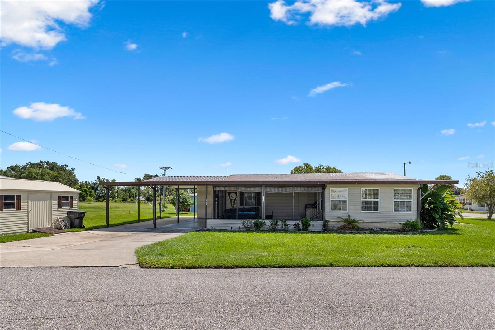 BREEZE HILL ~ A 55+ Community on Lake Walk In Water where residents Own their Land and have a Low HOA fee! This well-maintained 2 BD/ 2 BA home is a great place for year-round residency or for a winter retreat. The living/dining combination circles the attractive kitchen that has lovely oak cabinetry, stainless appliances and a breakfast bar. The primary suite has a walk-in closet and its bathroom has a single vanity and a shower. The second bathroom is convenient to the guest bedroom and to the main living areas. A 15’x12’ family room stands off from the kitchen giving more comfortable, indoor living space. From the family room, step outside to a screened porch with ceiling fan to a relaxing area to enjoy morning coffee or a cool evening sunset. The extra large carport houses the utility room with laundry facilities and storage. A nice sized storage building is conveniently located by the driveway. The Breeze Hill community is on the largest lake in Polk County, Lake Walk in Water which is known for its trophy bass! has a low HOA fee; there is an annual HOA fee of $200 that is required for the private roads maintenance; plus, there is an Optional HOA fee for amenities: the heated pool, clubhouse, private boat ramp, fishing pier and more. This peaceful, rural community in Polk County is just a short distance to shopping, medical and restaurants; Kissimmee River State Park is nearby and it’s less than an hour’s drive to Vero Beach. Call Today ~ Come See This One!