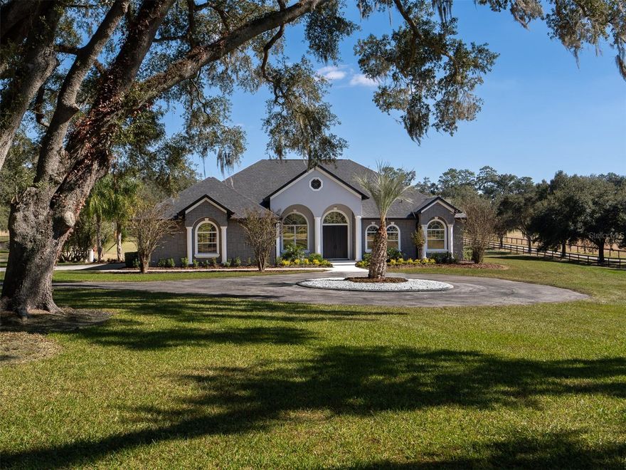 Located on NW 80th Ave, one of the most desirable and sought after streets in Ocala for its beauty, serenity, and unbeatable location, this exceptional 10-acre property is just 14 minutes from the World Equestrian Center and Golden Ocala, offering both convenience and peaceful country living. Fully fenced and shaded by beautiful oak trees, the property features a welcoming circular drive, while the expansive open backyard acreage provides the perfect opportunity to add paddocks and build a barn. The home includes luxury vinyl flooring throughout and an inviting open floor plan with 3 bedrooms and 3 full bathrooms. The kitchen boasts stunning countertops, a stylish backsplash, and updated appliances, flowing seamlessly into a warm living room complete with built-in cabinetry and a cozy fireplace. The primary suite offers a spa-like retreat with his-and-her vanities, a large soaking tub, a walk-in shower, and an expansive walk-in closet with built-in shelving. An attached garage adds convenience and additional storage. Completing this impressive property is the covered back porch with outdoor kitchen space overlooking the in-ground pool and attached spa, perfect for relaxing or entertaining. With its ideal location, thoughtful features, and endless potential, this property offers an opportunity to create the equestrian lifestyle of your dreams.