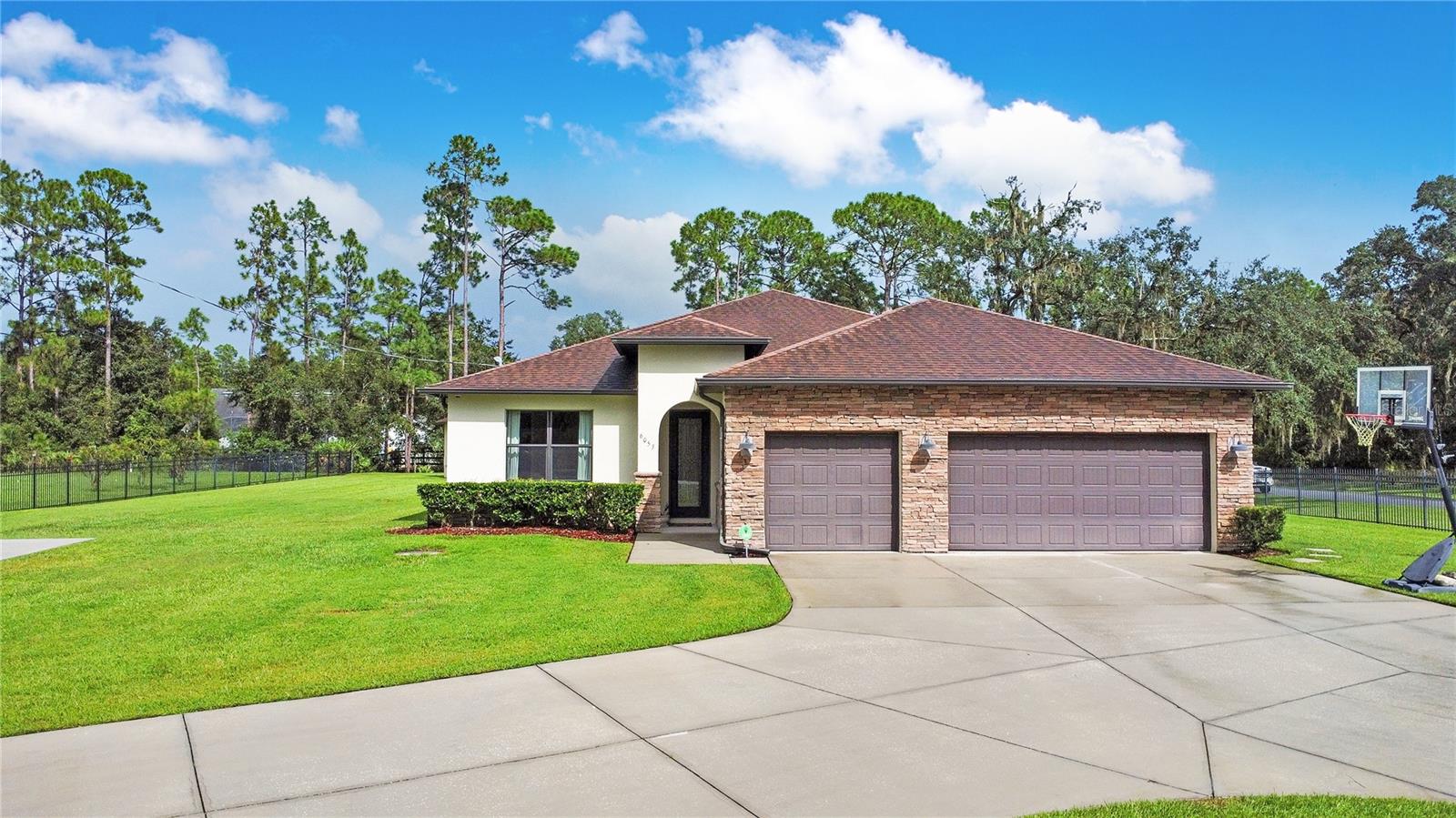 One acre, gated and set on a corner lot, with space to spread out: a main home that anchors, a guest house that stands apart, a pool built for weekends, and a three-car garage for everything else. The entry sets the tone: high ceilings, natural light pouring in, crown molding, wainscoting, and wide tile floors. It feels open, grounded, intentional. Off to the side, a second primary suite shows up early: coffered ceiling, double French doors, and a bathroom that’s all clean lines. Privacy from the jump. Then the house stretches wide. And the kitchen runs point: a massive island with seating, gas range with three ovens, and a walk-in butler’s pantry that doesn’t quit. Costco runs? Approved. This pantry gets your bulk-buy personality with counter space, storage, and a wine fridge tucked in. Everything spills into the dining and living spaces, where sliders pull the outdoors in. The main primary suite owns the back corner with direct lanai access, a swoon-worthy custom walk-in closet, and private ensuite that feels quietly luxurious. Bedrooms three and four share their own tucked-away wing with a full bath. Even the laundry is oversized, with a sink and storage that make it feel less like a chore. Closet organizers in every room mean the daily chaos actually has a place to go. Step out back and good luck coming in early. Oversized paver patio, pool with spa and stacked-stone spillway, built-in gas firepit poolside, and string lights overhead. It’s the kind of setup where conversations run long, the nights stretch later, and nobody wants to head inside. Covered lanais with ceiling fans and TV-ready walls off both the main home and guest house—it’s built to work year-round, whether it’s game day or a quiet Sunday morning. And the detached guest suite? It’s not an afterthought—it’s its own thing. Private entrance, living room, kitchenette, bedroom, full bath, and its own lanai. Perfect for multigenerational living, long stays, or when you just want extra breathing room. Details keep stacking: three-car garage, oversized laundry, central vacuum system, automatic gate, full perimeter fencing, oversized driveway with parking pad, ready for RV or boat parking. Located in a spot with a rare balance: acreage and privacy when you want it, access when you need it. Lake Nona’s Medical City, OIA, downtown Orlando, and the beaches are all within easy reach. This is living at its best—space, privacy, and a setup that works as hard as it plays.
