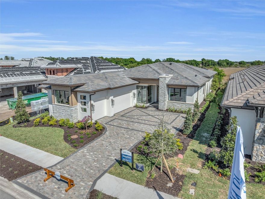 Lee Wetherington Homes Award Winning Sapphire fully furnished Model Home in Wild Blue at Waterside is now available for purchase and leaseback.  Best Overall Winner at the 2024 Parade of homes, this beautiful home exudes modern elegance, luxurious living and dramatic moments including the stunning 10ft tall custom iron pivot front entry door with crushed glass. A palette of white oak, veined marble stone, geometric tiles and touches of gold can be seen throughout. Wild Blue is located in the Waterside Village of Lakewood Ranch.  Residents will enjoy an exclusive resort-style clubhouse where a concierge service fulfills the desires of active and social lifestyles. The clubhouse will feature a theater, fitness studio, workout classrooms, golf simulator, billiards, an expansive pool complex with restaurant and patio bar, two swimming pools, a yoga lawn and putting green, Also enjoy miles of walking trails and the mid-way sport complex with 8 pickle ball courts, 6 tennis courts, Pro-Shop, dog park & playground. Landscape maintenance and irrigation included.List price includes all furnishings, electronics and artwork and is net of the first 12 months leaseback.