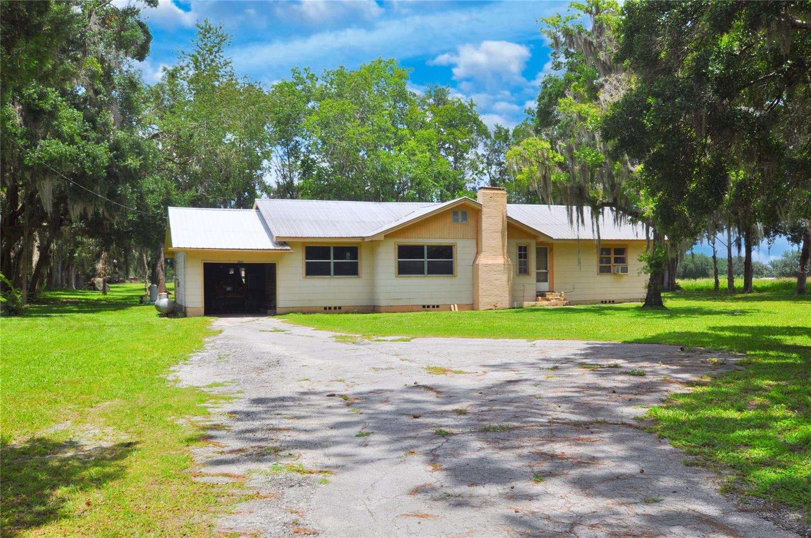 VINTAGE CHARM JUST OUTSIDE THE CITY! Discover the character and warmth of this classic 1952 home, set on a full acre along scenic State Road 121, just a mile south of downtown Williston. With over 1,500 sq. ft. of living space, this 3 bedroom, 2 bath home blends vintage appeal with practical updates. Inside, you’ll find tongue-and-groove wood walls in the dining and living rooms, a cozy wood-burning fireplace, and a bright kitchen that opens to a screened porch/mud room connecting to the garage. Enjoy peace of mind with a durable metal roof and stay connected with high-speed fiber internet from Fiber by Central Florida. A paved driveway leads to the attached one-car garage, offering convenience and extra storage. This is a rare opportunity to own a solid, character-filled home on a spacious lot in a great location close to town but with a true country feel. Come make it your own!