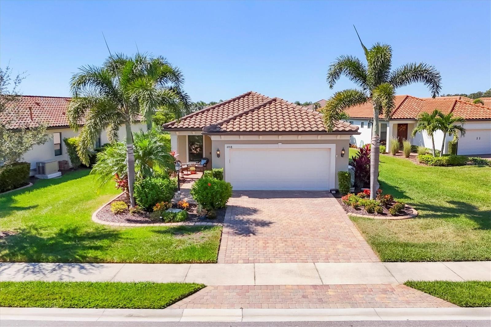 Welcome to Del Webb Lakewood Ranch and this adorable, highly upgraded Contour model featuring a superb water view and a gorgeous 2 year new saltwater pool surrounded by custom travertine pavers and an oversized lanai with remote-control storm shutters all the way around. The custom landscaping with decorative curbing and accent lighting enhances the expansive curb appeal, which offers exceptional privacy and a perfect setting to enjoy sunset views over the pond while relaxing in your no-see-um screened lanai. Step inside this meticulously maintained home, where porcelain tile floors and custom crown molding set an elegant tone throughout. The chef’s kitchen is a showstopper, featuring KitchenAid appliances, granite countertops, a custom tile backsplash with under-cabinet lighting, pull-out shelving in all lower cabinets, and an oversized island that seats three—ideal for cooking, entertaining, or casual dining. The master bedroom suite offers a tranquil retreat with water views, porcelain tile flooring, ceiling fan, and a spa-like bath complete with dual sink vanity with drawers, a tiled step-in shower with upgraded glass door, private water closet, linen closet, and a large walk-in closet. The guest bedroom is spacious and bright, featuring a walk-in closet, recessed lighting, and easy access to the guest bath. The cozy den provides flexible space for a home office, craft room, or additional guest area. Additional highlights include a whole-house generator, remote-control hurricane blinds, hurricane panels, epoxy garage floor, designer lighting and hardware, upgraded trim package, and a new water heater (2024). Del Webb Lakewood Ranch offers a vibrant, amenity-rich 55+ lifestyle with tennis, pickleball, bocce, fitness center, resort and lap pools, on-site restaurant and bar ($500 annual food & bev fee) & a full-time Lifestyle Director curating endless activities—all within a golf cart-friendly gated community. Ideally located near Sarasota, Bradenton, Tampa, and award-winning Gulf Coast beaches, this move-in ready home is your perfect opportunity to embrace Florida living at its best—schedule your showing today!