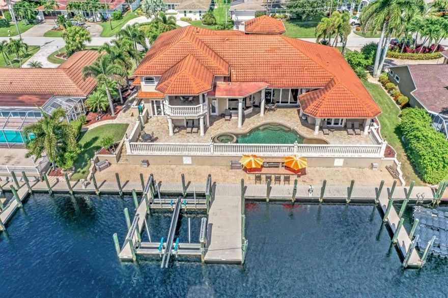 Southern-exposure pool home with direct gulf access on a 200 ft wide canal. Boaters, car-lovers, avid entertainers or large families craving quality time together. Multiple boat slips include a 60,000 lb lift, ensuring room for all your prides and joy. A Mediterranean-inspired masterpiece offering more than 6,579 sq ft of luxurious living space with artistic works of paint and granite. This 4 bedroom, 3.5 bath home has Elegance and Grandeur at every turn. The enormous gourmet kitchen, the dining room with mitered glass, a piano loft overlooking the great room and dream patio that overlooks the pool. There are main-floor and second-floor master suites along with a bonus room that could be easily made into a third master bedroom. A one of a kind finished 9 car garage with A/C that includes a Pool side bar and game room put this home over the top, giving you the ultimate Florida lifestyle! 120' of seawall, pavered circular driveway, centrally located and so much more!   Don't miss out on this once in a lifetime property! Room Feature: Linen Closet In Bath (Primary Bedroom). Room Feature: Linen Closet In Bath (Primary Bedroom).