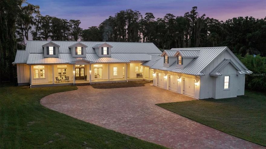 A captivating waterfront estate in Odessa awaits! Custom built in 2020, this modern farmhouse sits on 3.68 private acres surrounded by mature trees and a sprawling lawn that leads to your private dock along the gentle shores of Lake Alice. Gated and private, the meandering drive leads to the intricate herringbone paver courtyard where this five-bedroom, three-and-a-half bath, 5,310 sq ft. home sits alongside the 3-car garage with unfinished attic space, connected by a covered walkway. The sweeping front porch spans the entire front of the home and features multiple French doors that are ideal for indoor-outdoor living and entertaining. Through the front doors, you are greeted by a vaulted entry, durable wide-plank engineered hardwood flooring, and custom millwork. The formal dining space to your right can comfortably hold your largest table and the impressive chandelier offers a subtle hint to the quality of design found throughout the home. Farther into the home you find the informal living spaces with stunning coffered ceilings, cozy fireplace, and French doors that overlook the grounds and waterfront. The transom windows give the room ample natural light throughout the day. Overlooking the living space is the spacious gourmet kitchen with oversized island featuring gleaming quartz counters, statement lighting, and marble backsplash. Built for your inner chef, the appliance suite includes a Sub-Zero fridge and industrial gas range with wall-integrated pot filler. The adjacent spice kitchen with butler pantry, prep space, and appliances ensure that any mess stays out of sight. The patio space features several living and entertaining spaces to choose from, with an outdoor kitchen and stone fireplace. After a day on the lake, rinse off in the outdoor shower and enter the home through the brick-floored mudroom with storage lockers to keep everything tidy and a full walk-in laundry room with plenty of storage space. In addition to the five bedrooms, a game room, study room, second informal living space, and a sound-proof home office makes living and working from home a breeze. If you are looking for a low-maintenance home, you’ll love this energy efficient home, as well as the sturdy metal roof, custom-designed HVAC, hurricane windows, whole-house water filtration system, top-of-the-line alarm system, and sound-dampening walls between each bedroom. Every thought has been given to this magnificent home, and it can now be yours. Call to schedule your private showing!